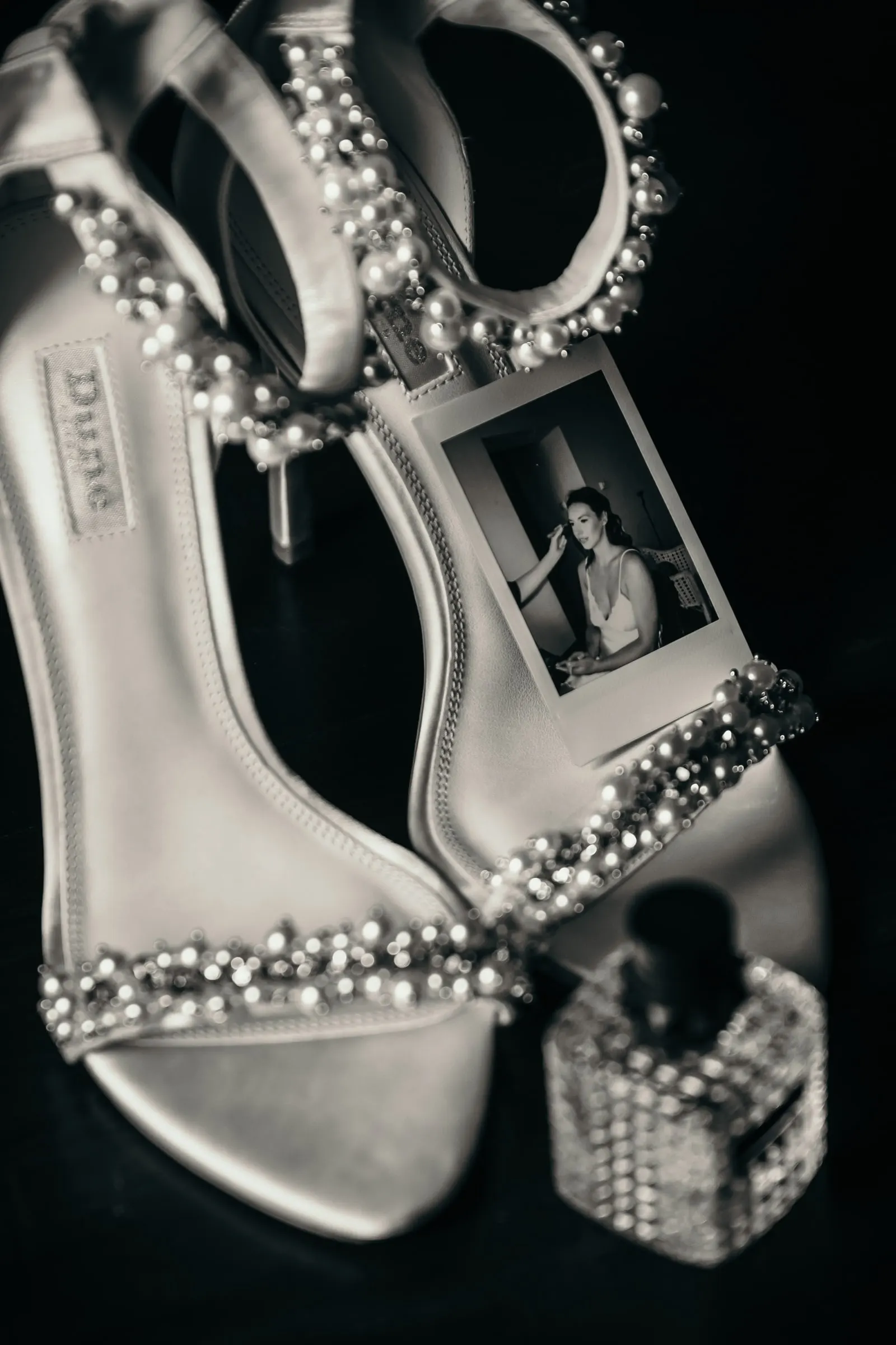 Bride’s jewelled sandals and perfume with a small printed portrait, black and white wedding detail