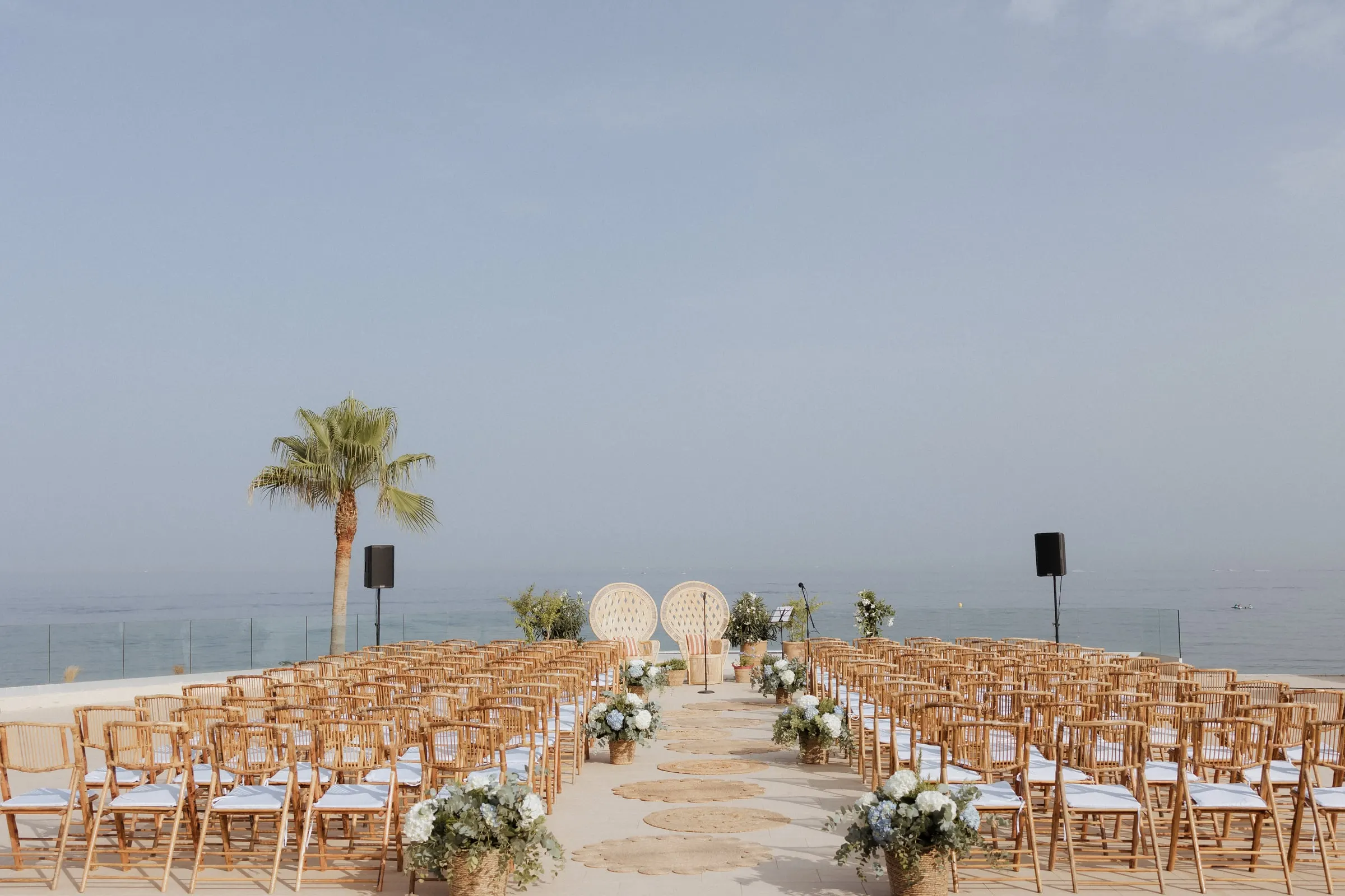 Ceremony set up on the seafront terrace with wooden chairs and white flowers, Barbillón, Marbella