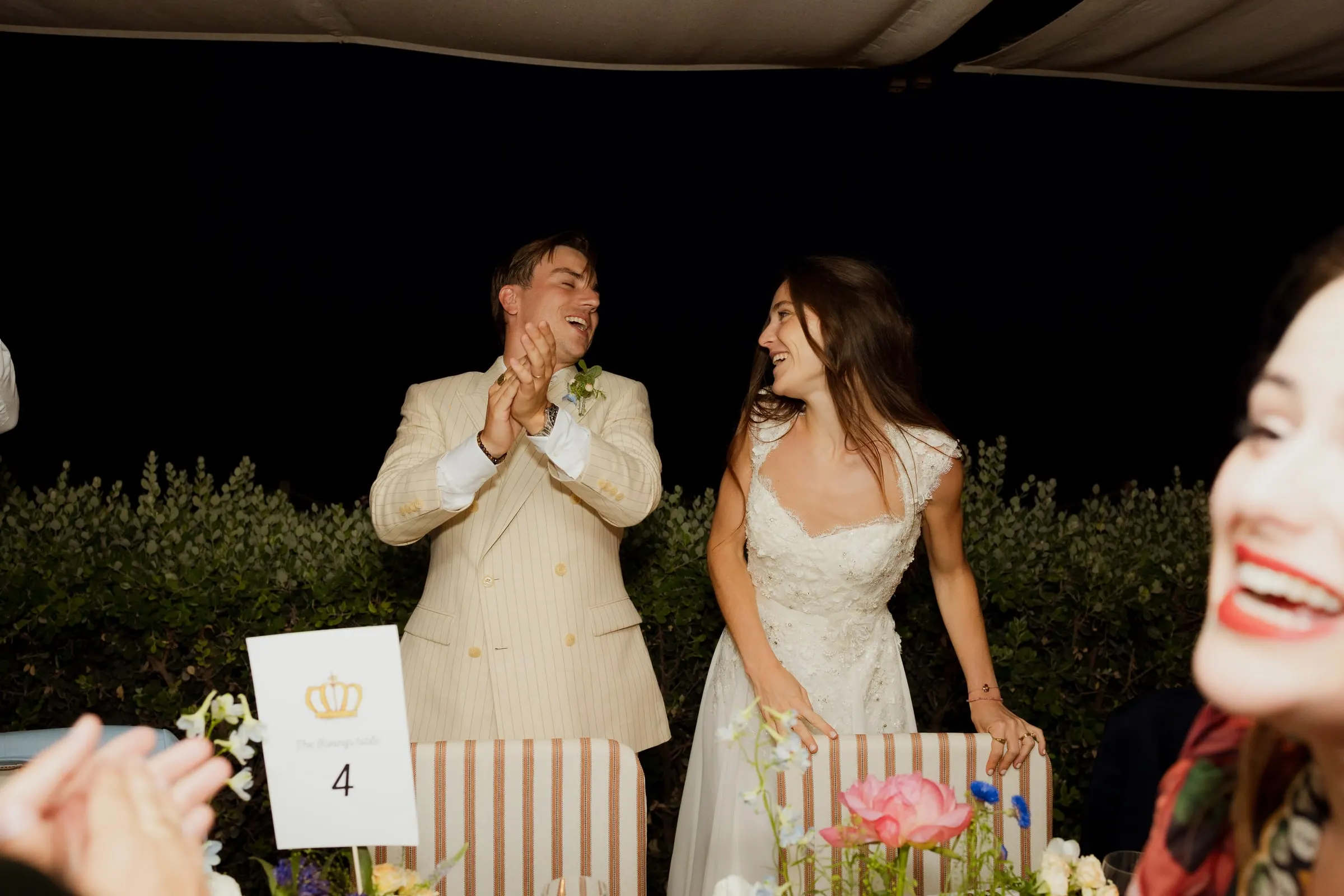 Groom applauding and bride laughing at the head table at night, Barbillón, Marbella