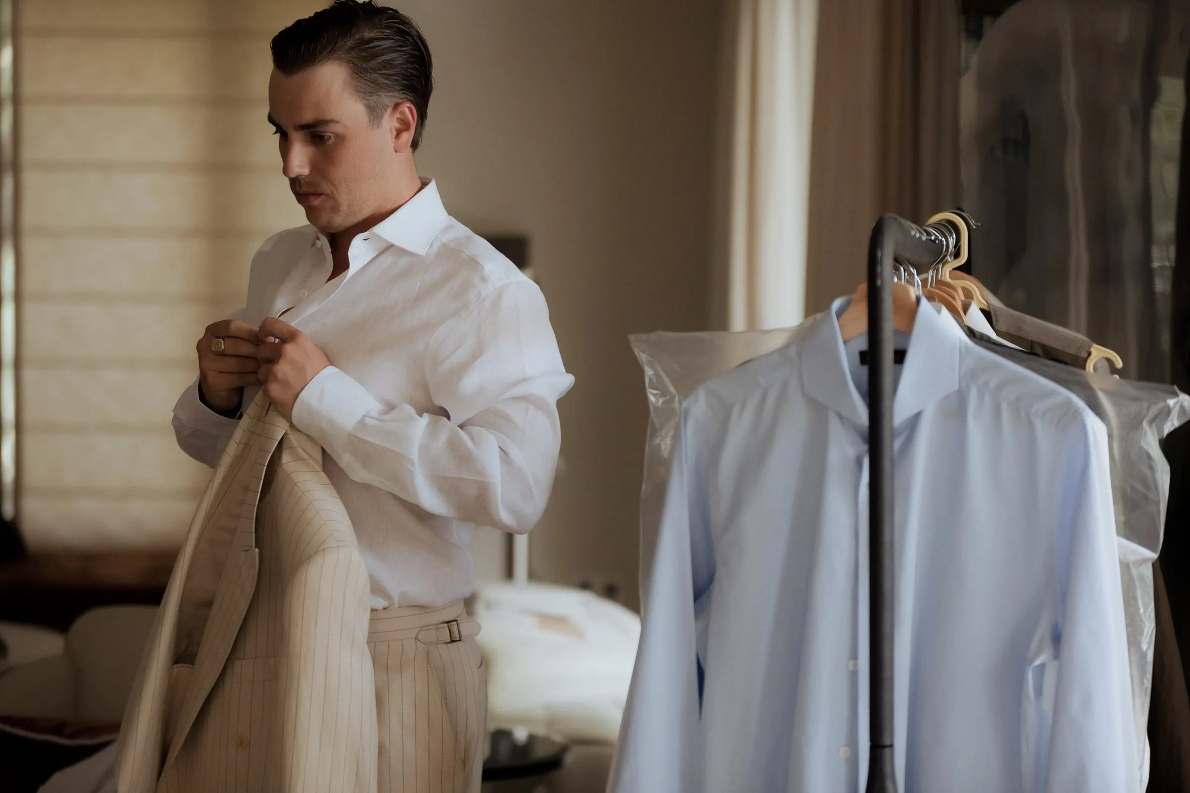 Groom in a white shirt taking his jacket from the clothes rail, Barbillón, Marbella