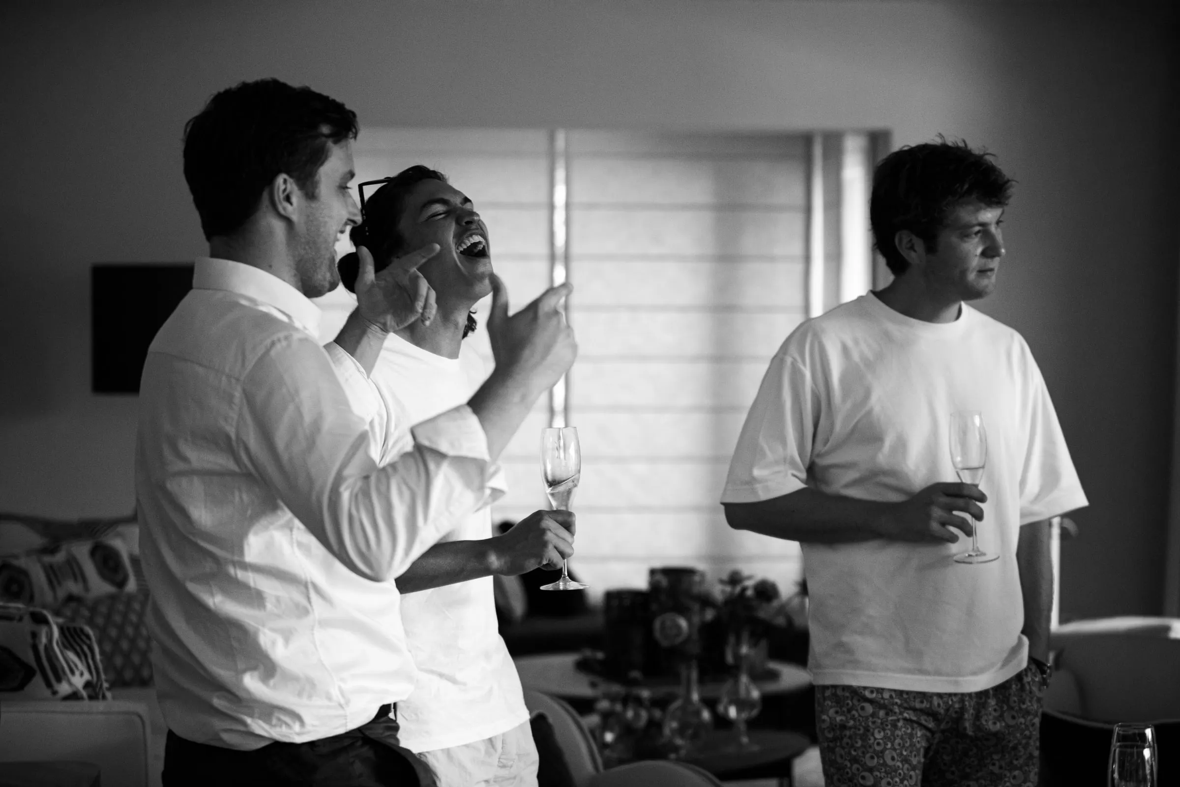 Black and white of three friends laughing with glasses in hand, Barbillón, Marbella