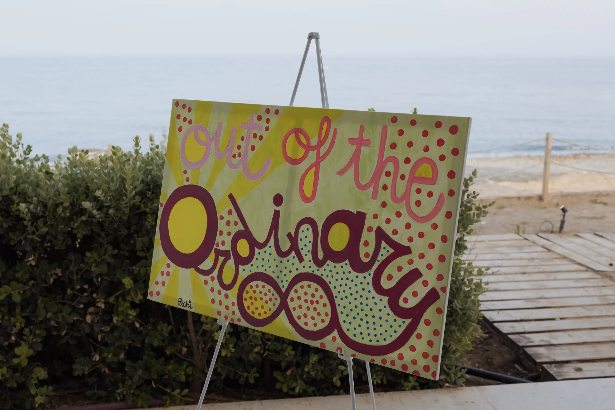 Hand-painted Out of the Ordinary sign on an easel above the beach, Barbillón, Marbella