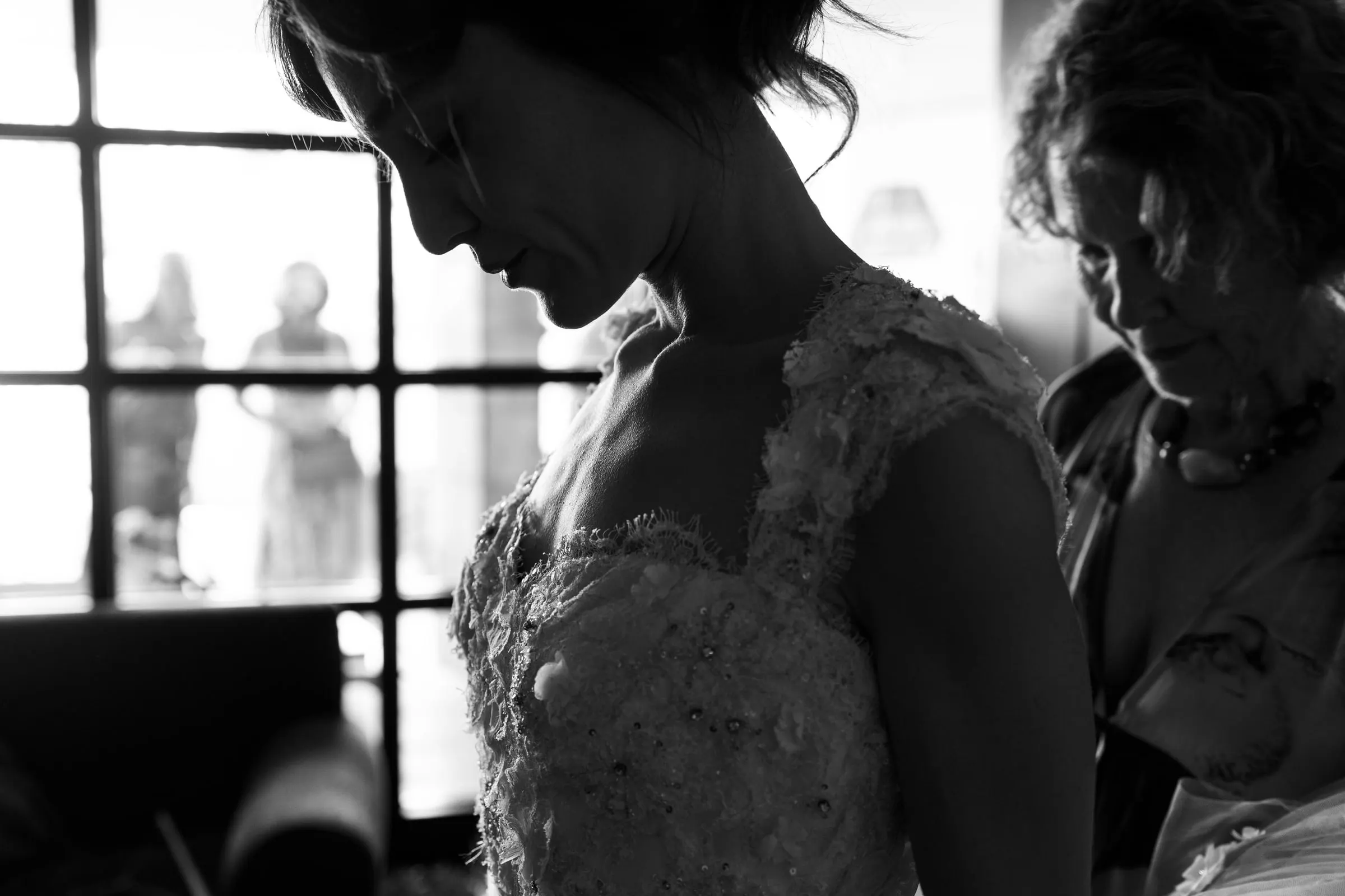 Black and white of the bride in lace as a woman adjusts her dress, Barbillón, Marbella