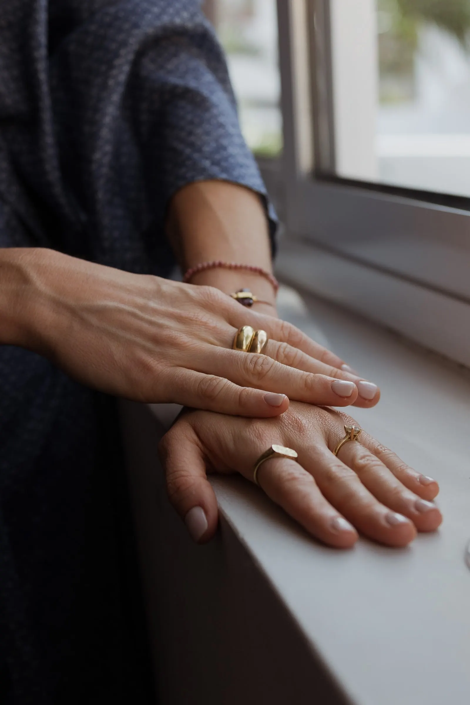 Close-up of hands with gold rings resting on a window ledge, Barbillón, Marbella