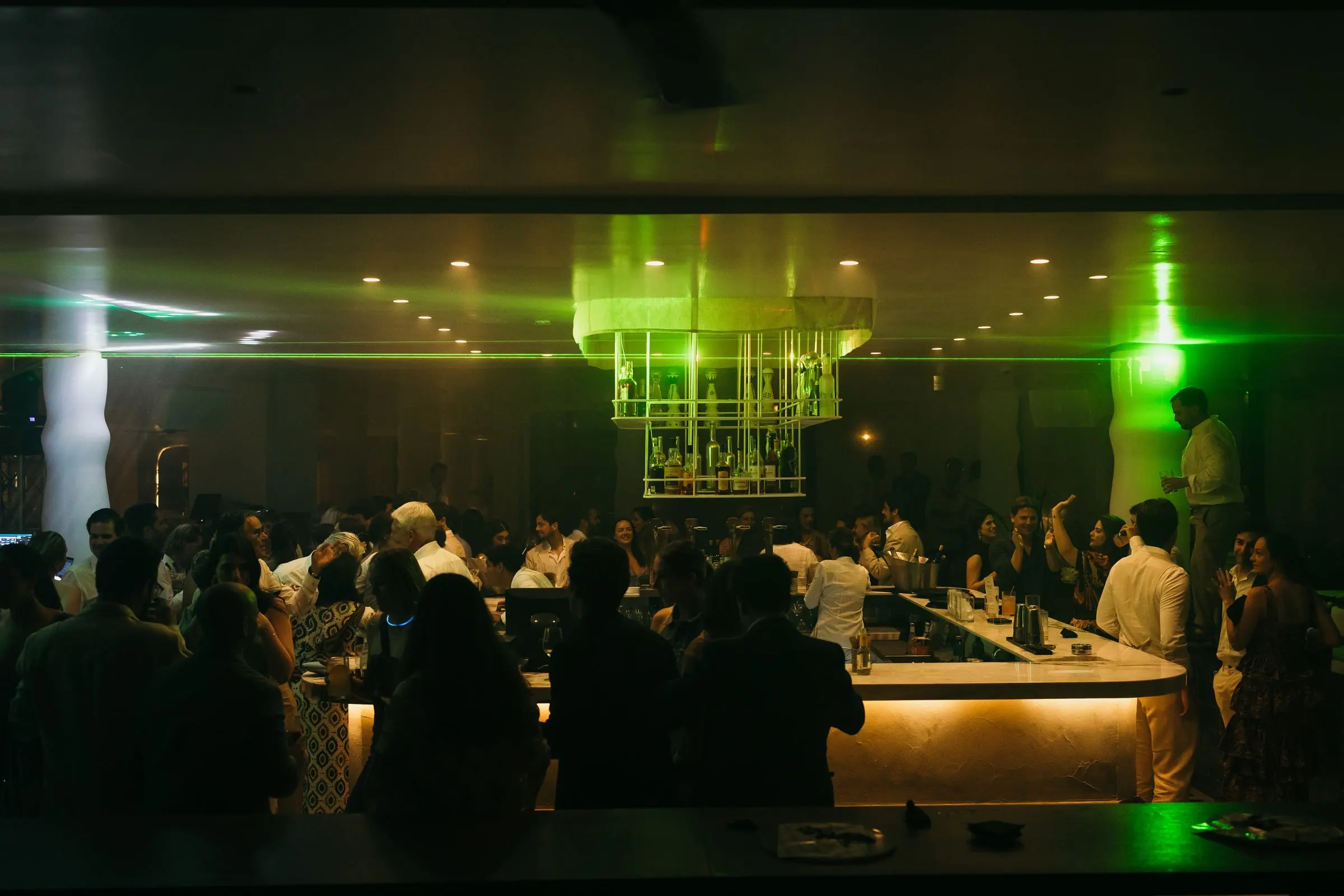 Crowded bar lit with green lights during the wedding party, Barbillón, Marbella