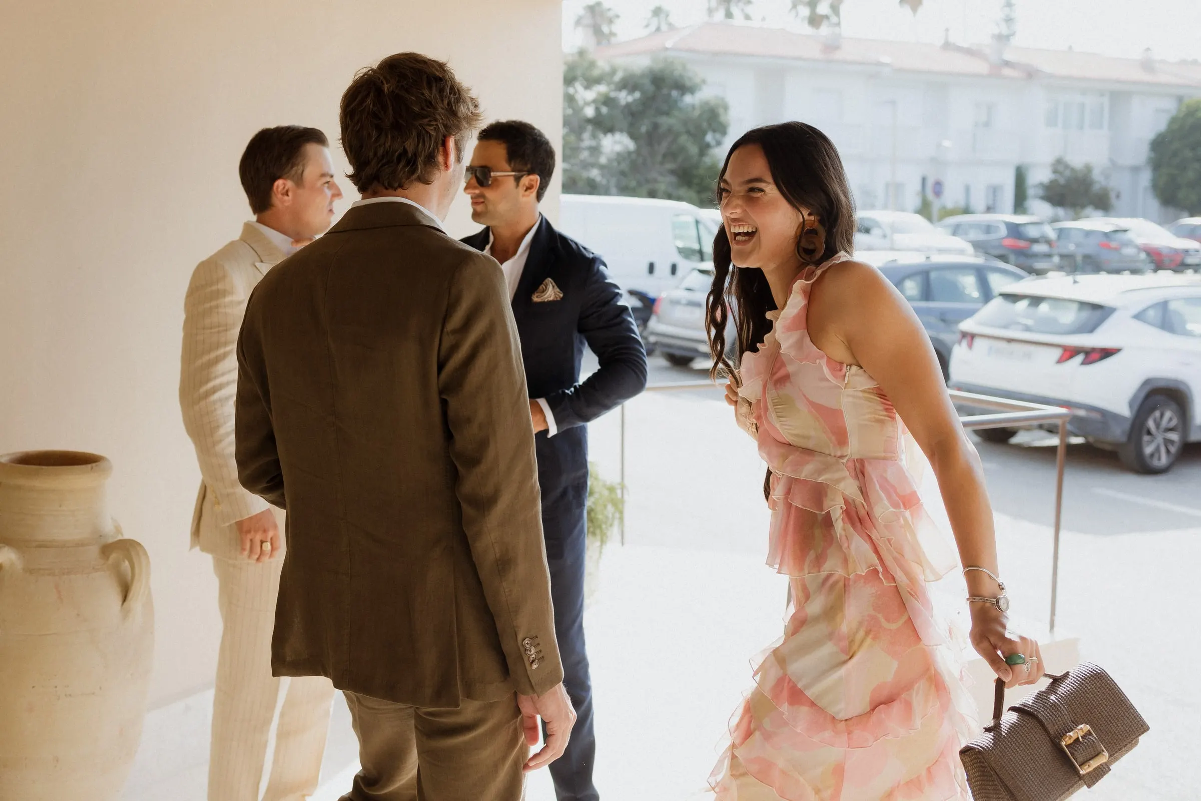Guest in a pink ruffled dress laughing as she greets friends on arrival, Barbillón, Marbella