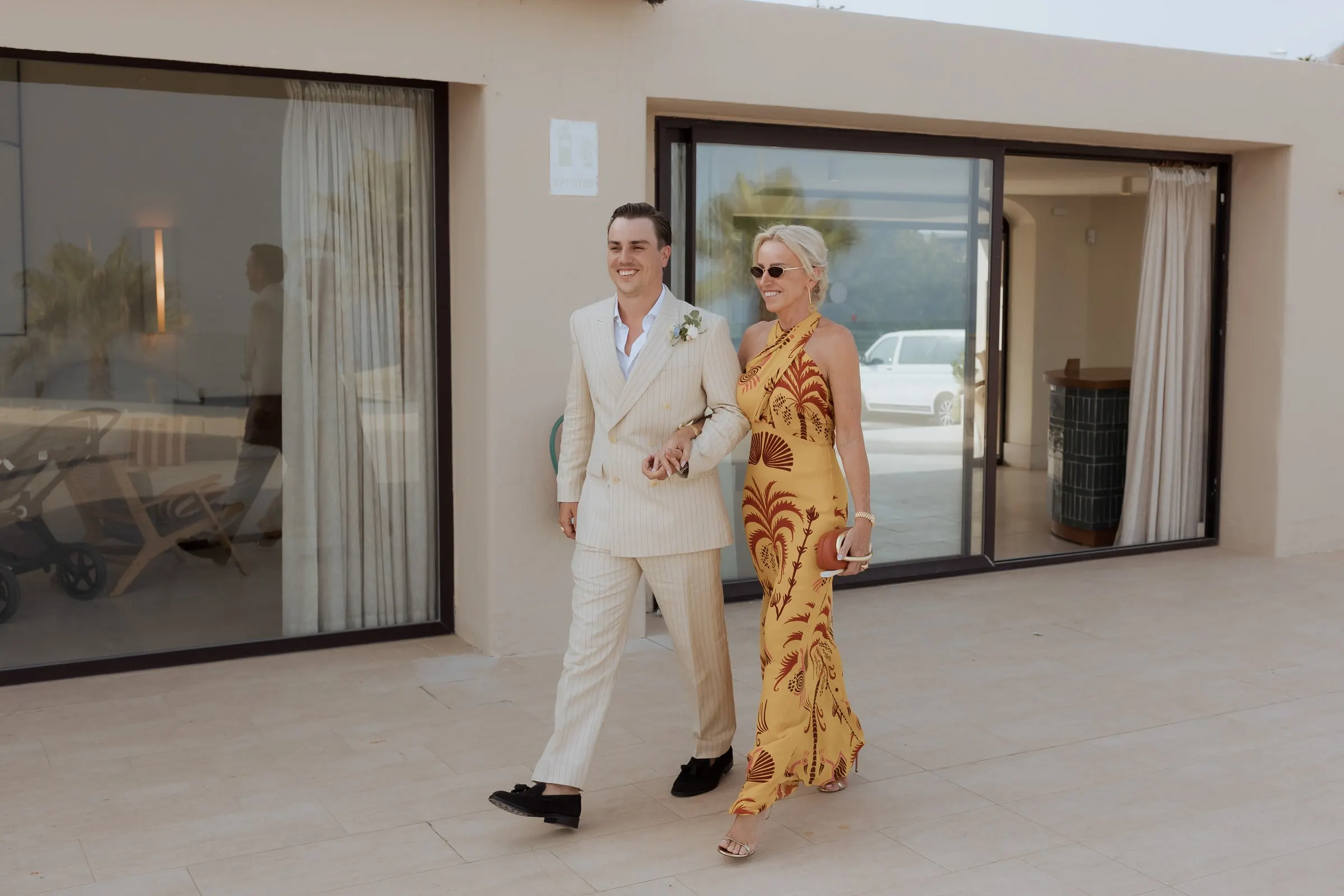 Groom walking arm in arm with a woman in a yellow dress outside the villa, Barbillón, Marbella