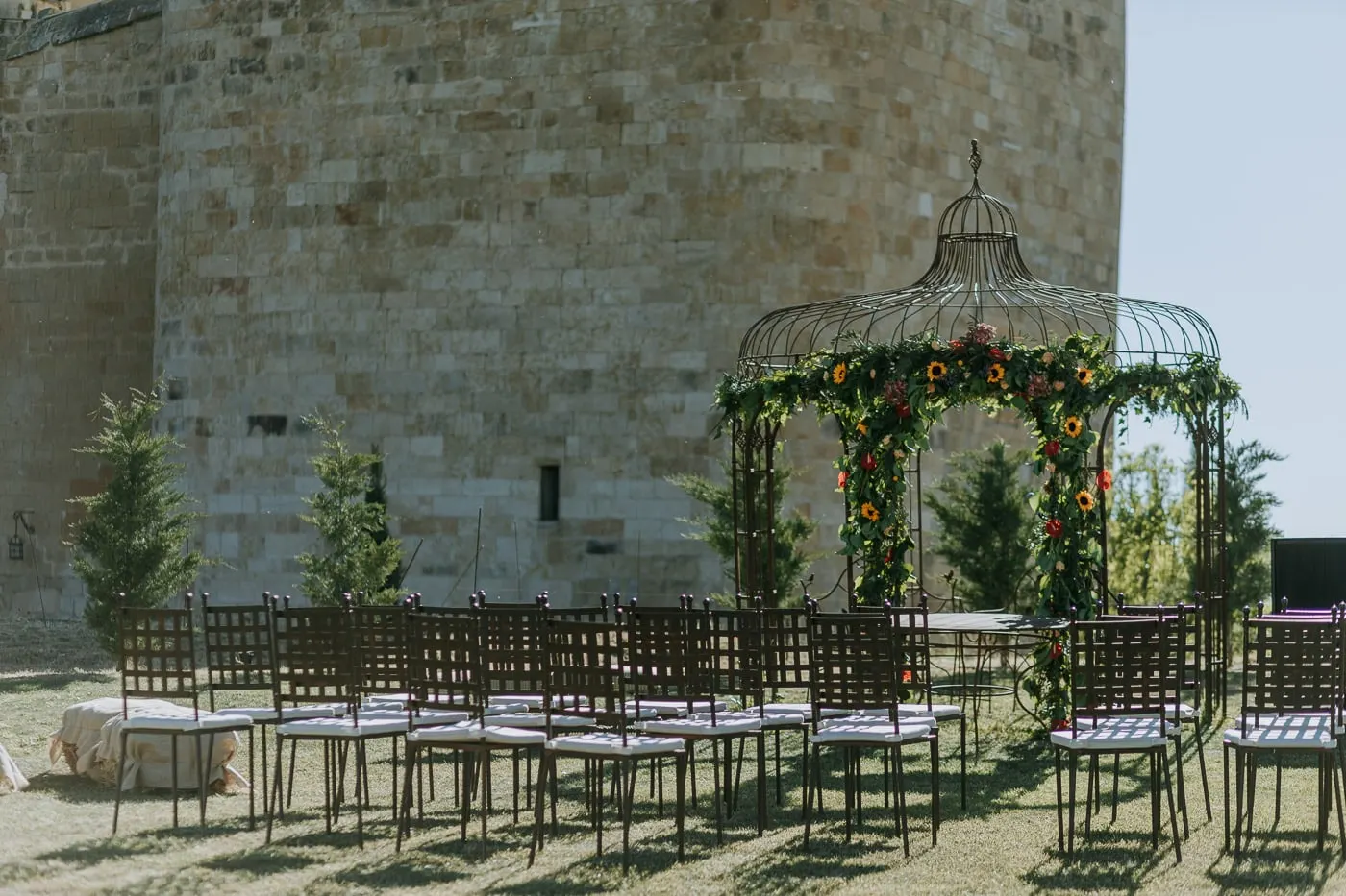 Iron gazebo with flowers and rows of chairs at the foot of the castle tower, Salamanca