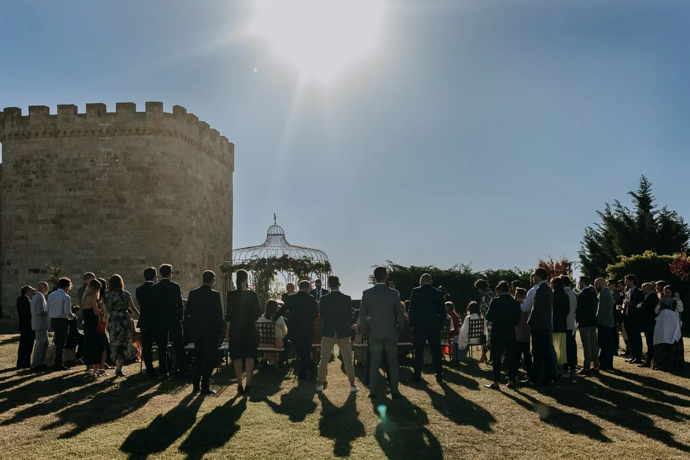 Guests gathered around the gazebo in the sun, with the castle tower behind, Castillo del Buen Amor