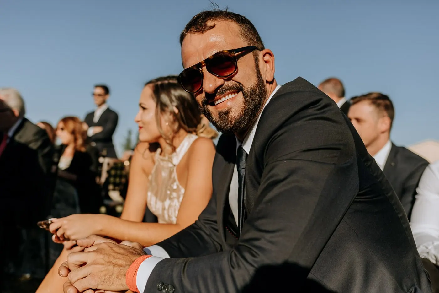 Guest in sunglasses smiling during the vows, Castillo del Buen Amor