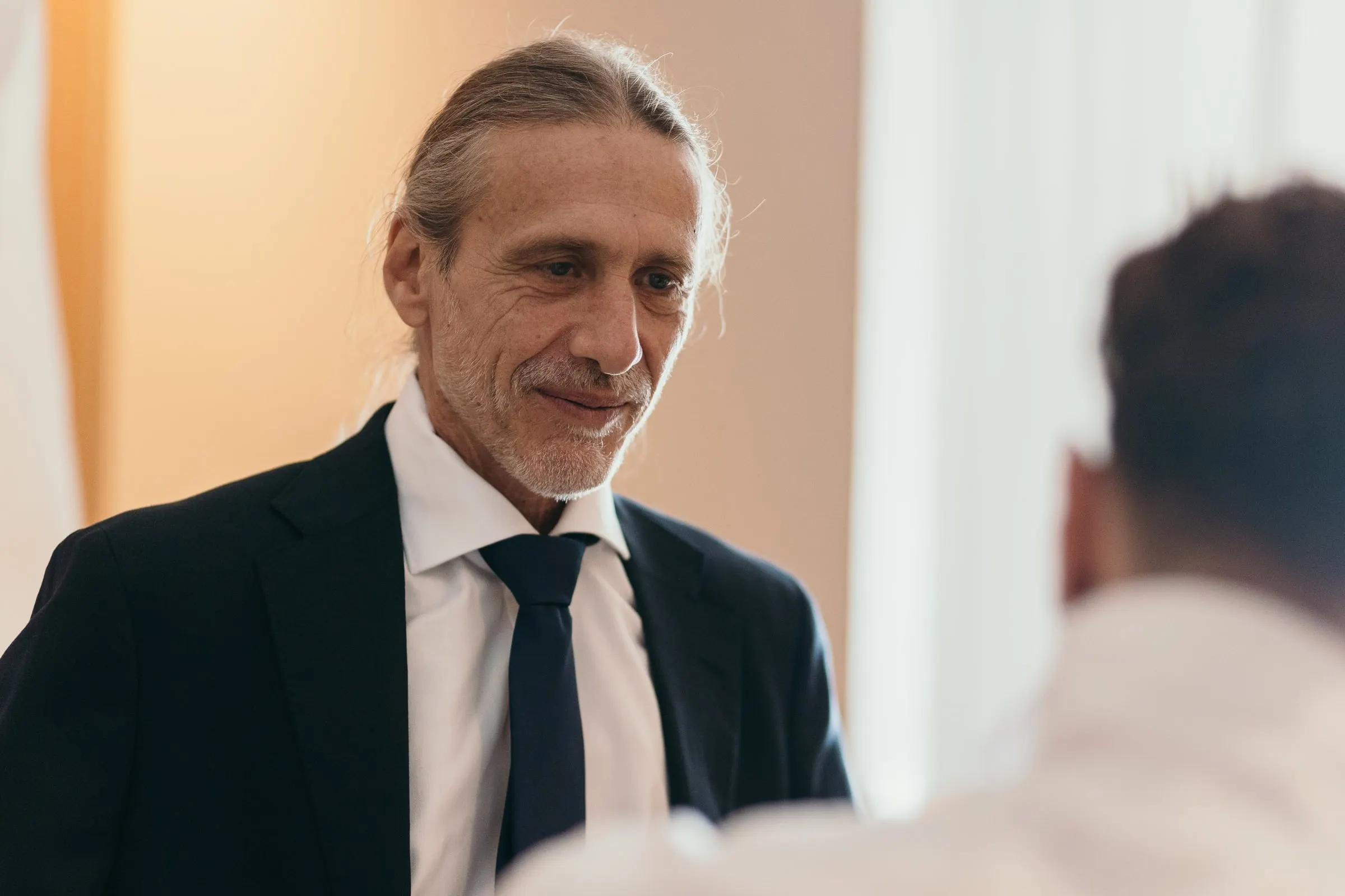 A smiling guest in a dark suit and tie during the preparations