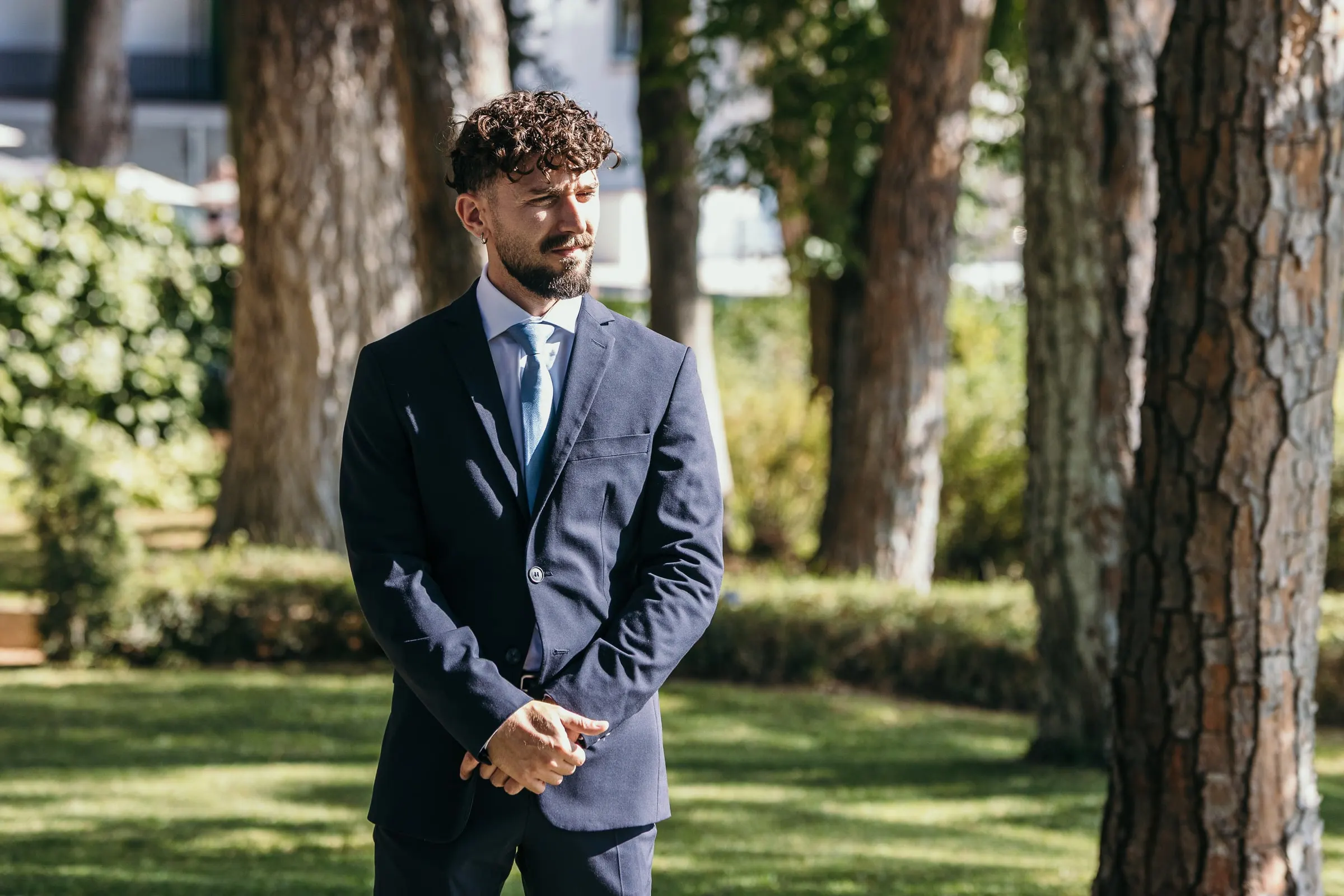 Vincent waits alone on the lawn under the tall pines before the ceremony