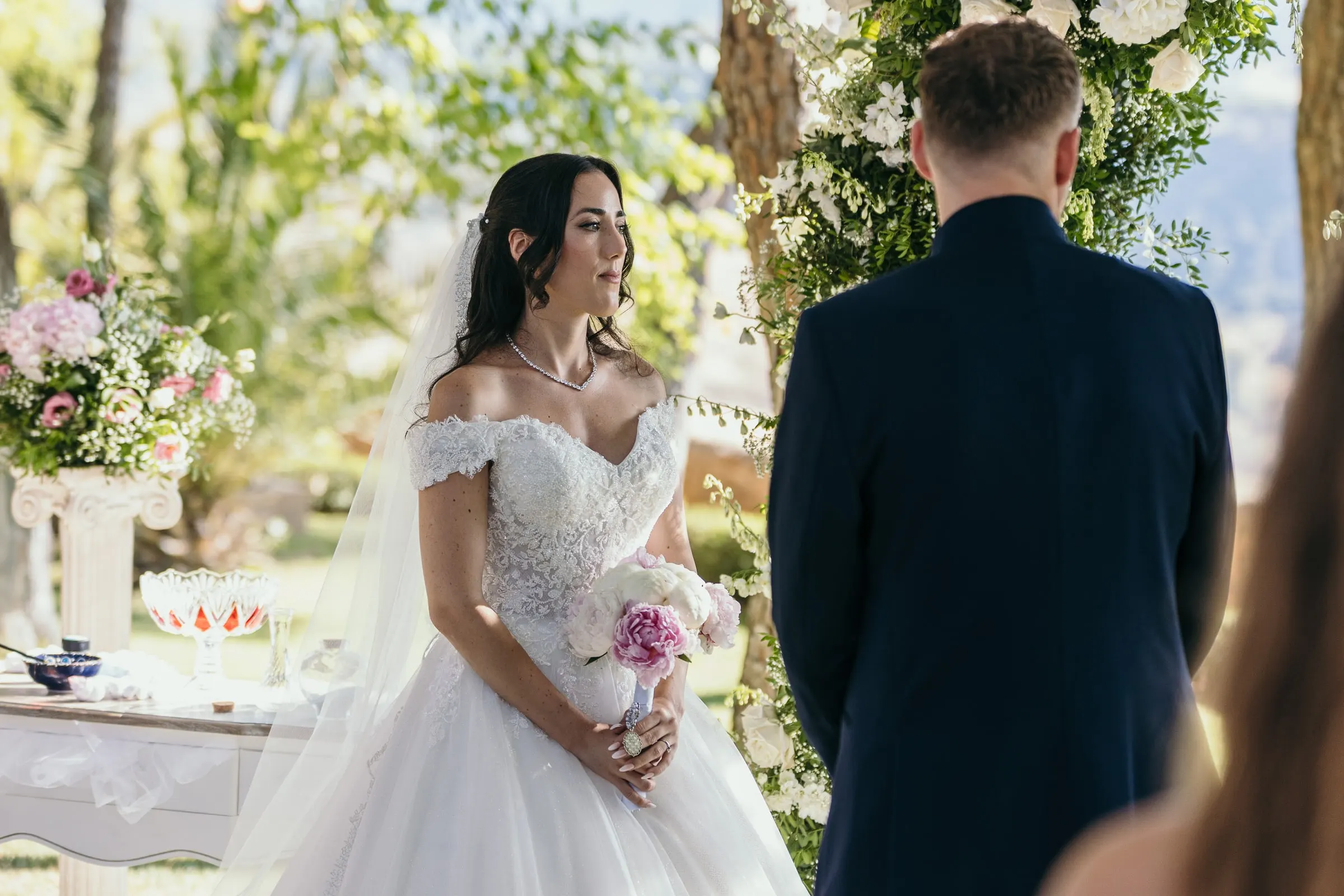 Sara faces Vincent at the altar, holding pink and white peonies