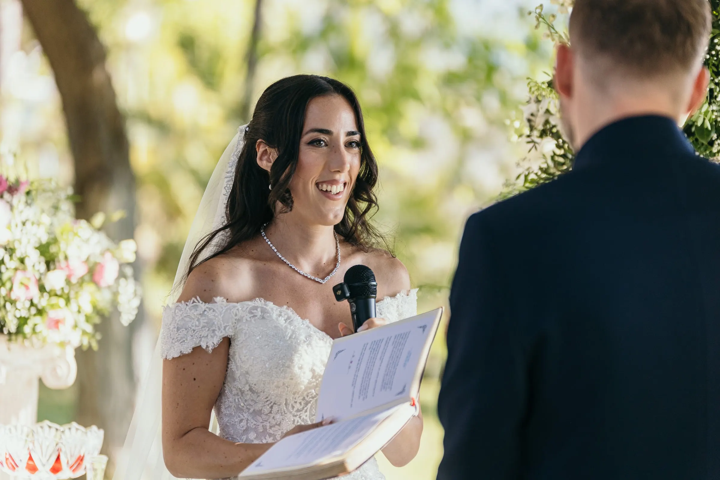Sara smiles as she reads her vows to Vincent with a microphone in hand