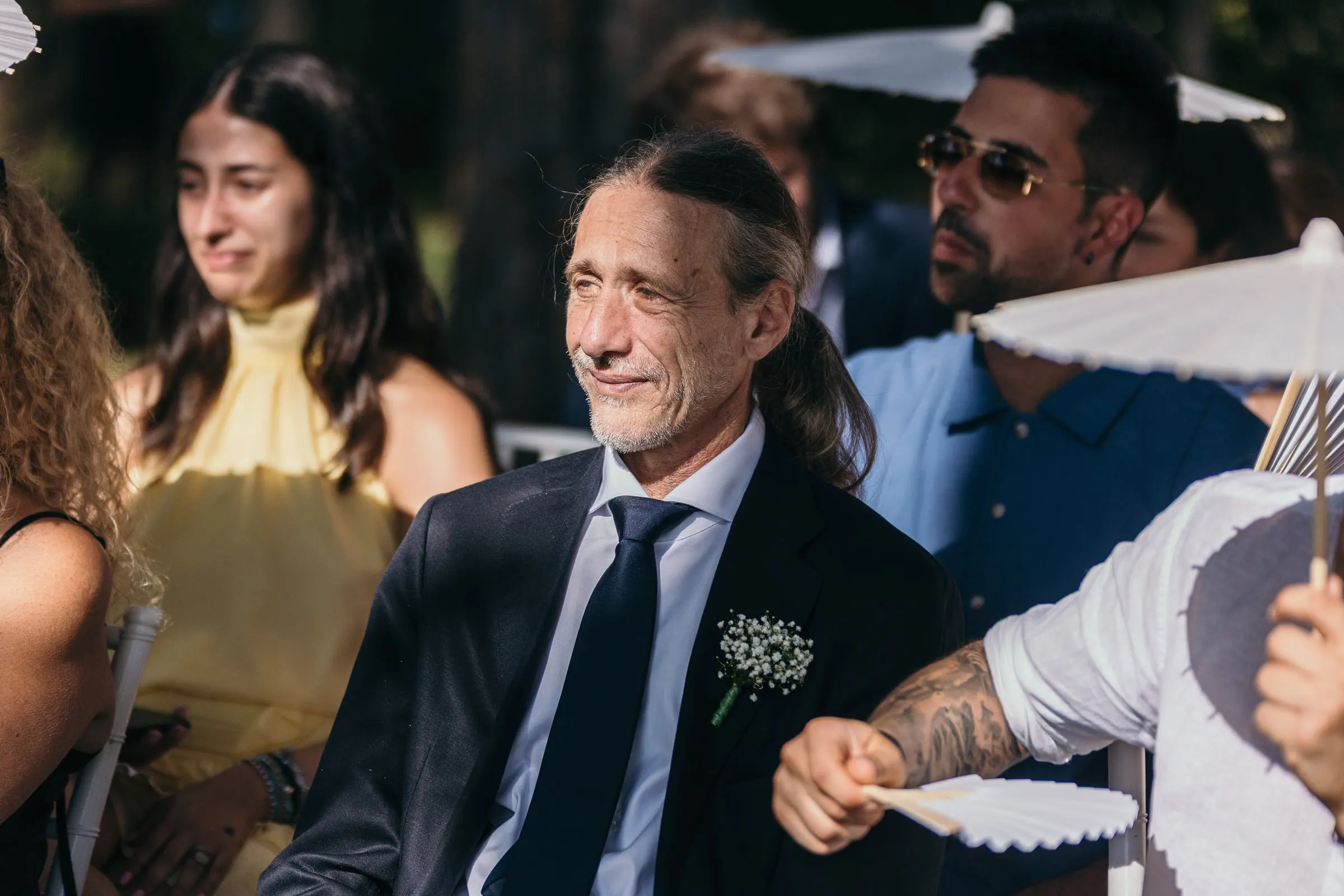 A guest laughs during the vows while others fan themselves