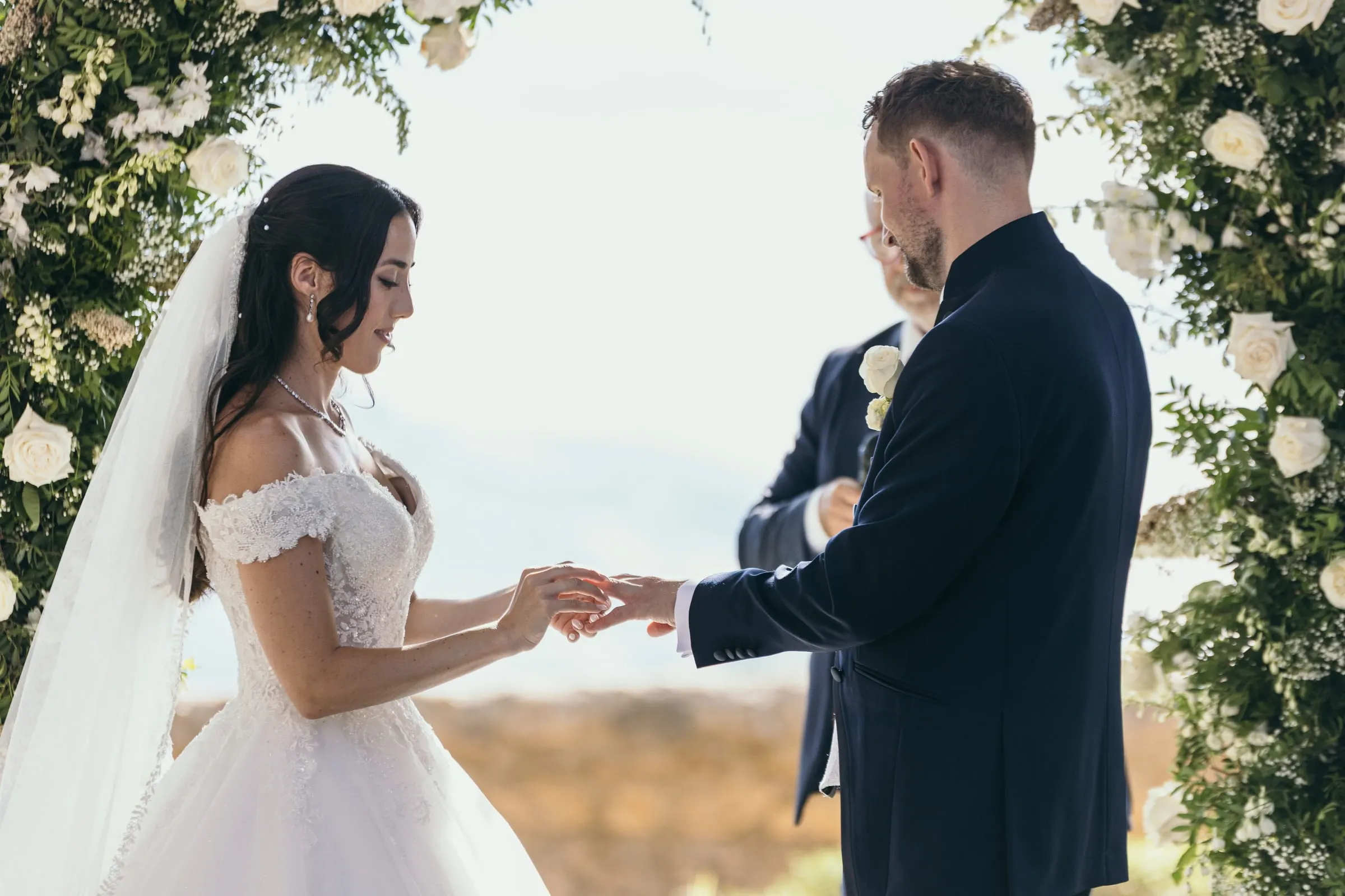 Vincent slides the ring onto Sara's finger at the garden ceremony