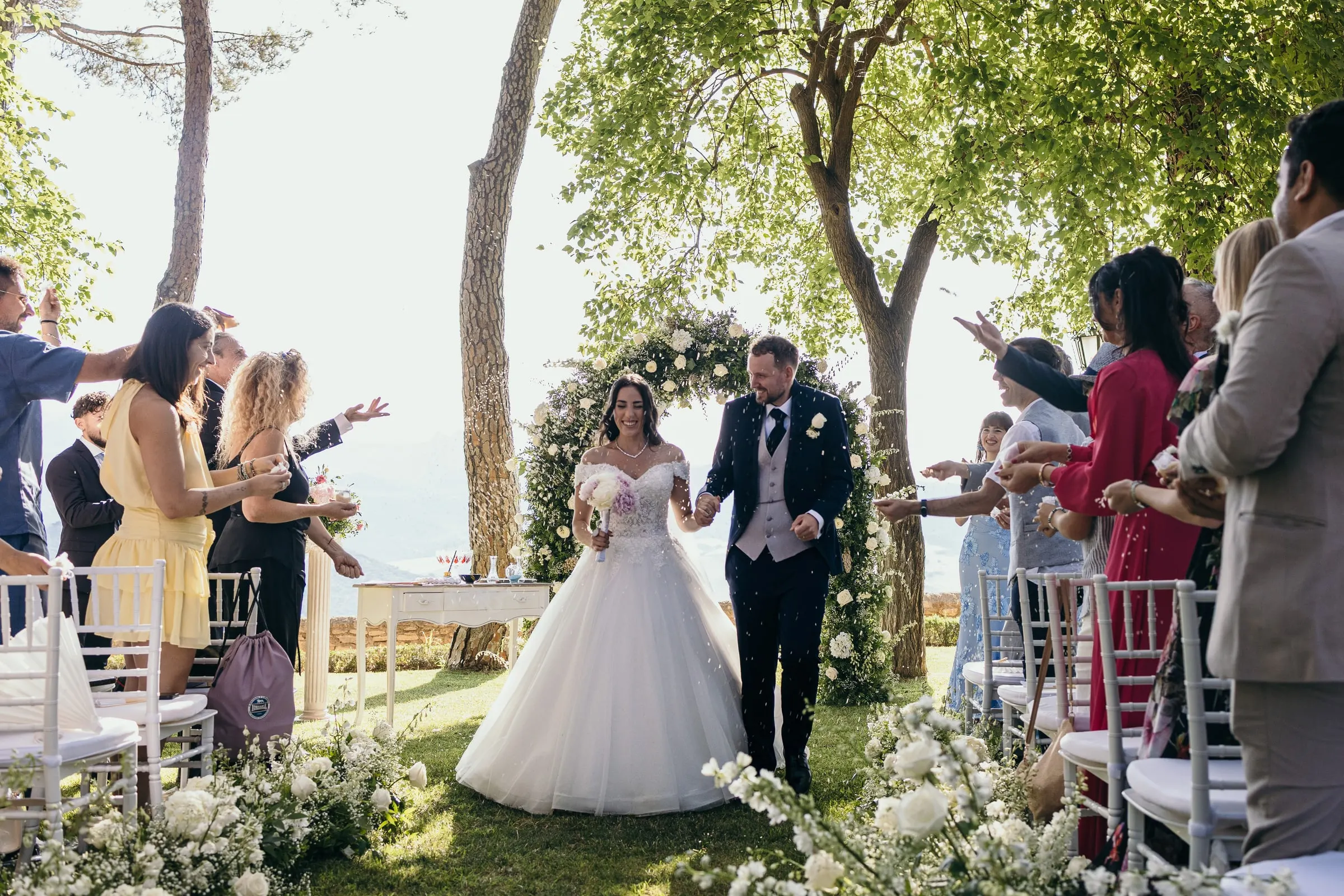 Sara and Vincent walk back down the aisle as guests cheer and throw petals