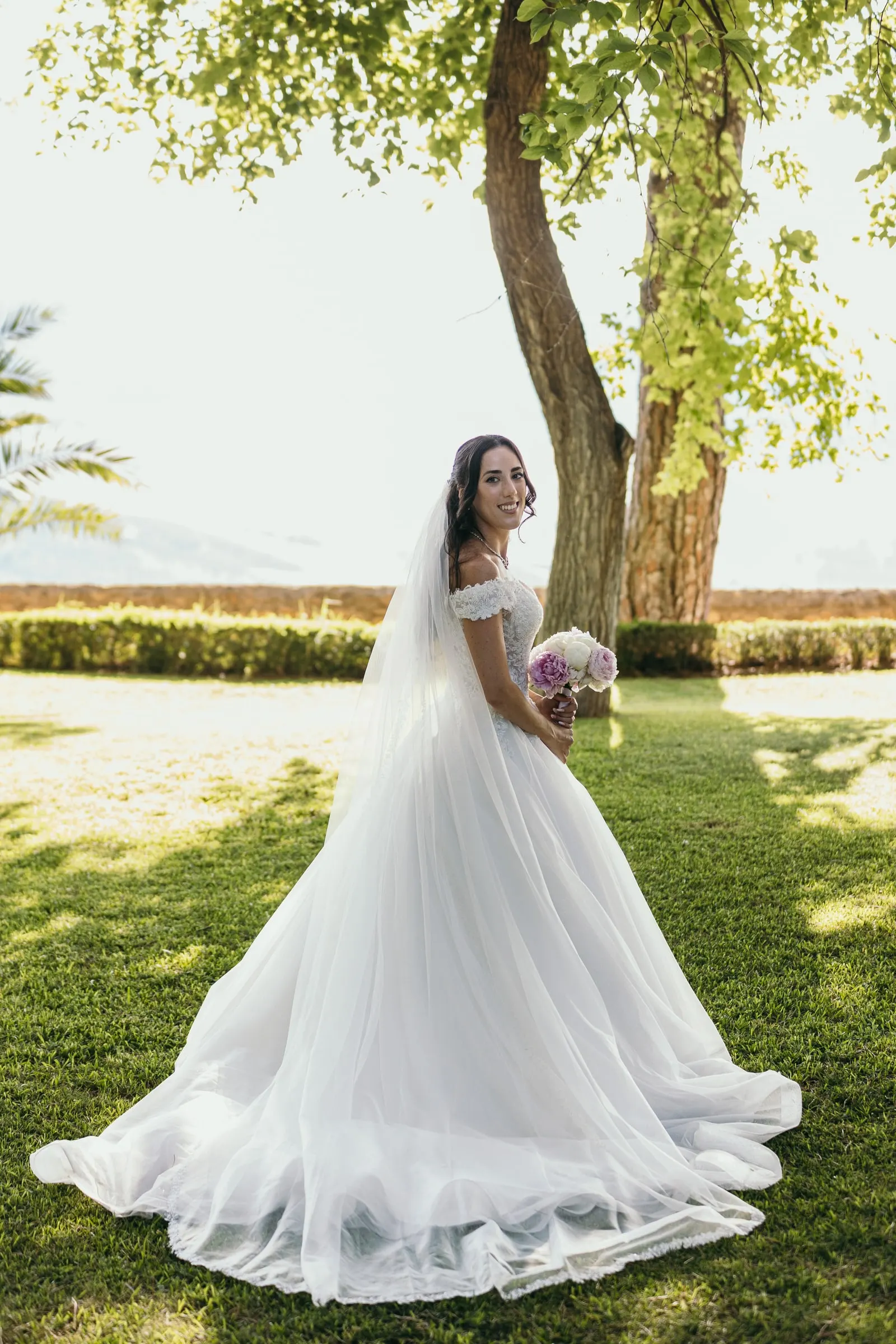 Sara stands alone on the lawn in her ball gown, her veil falling to the grass
