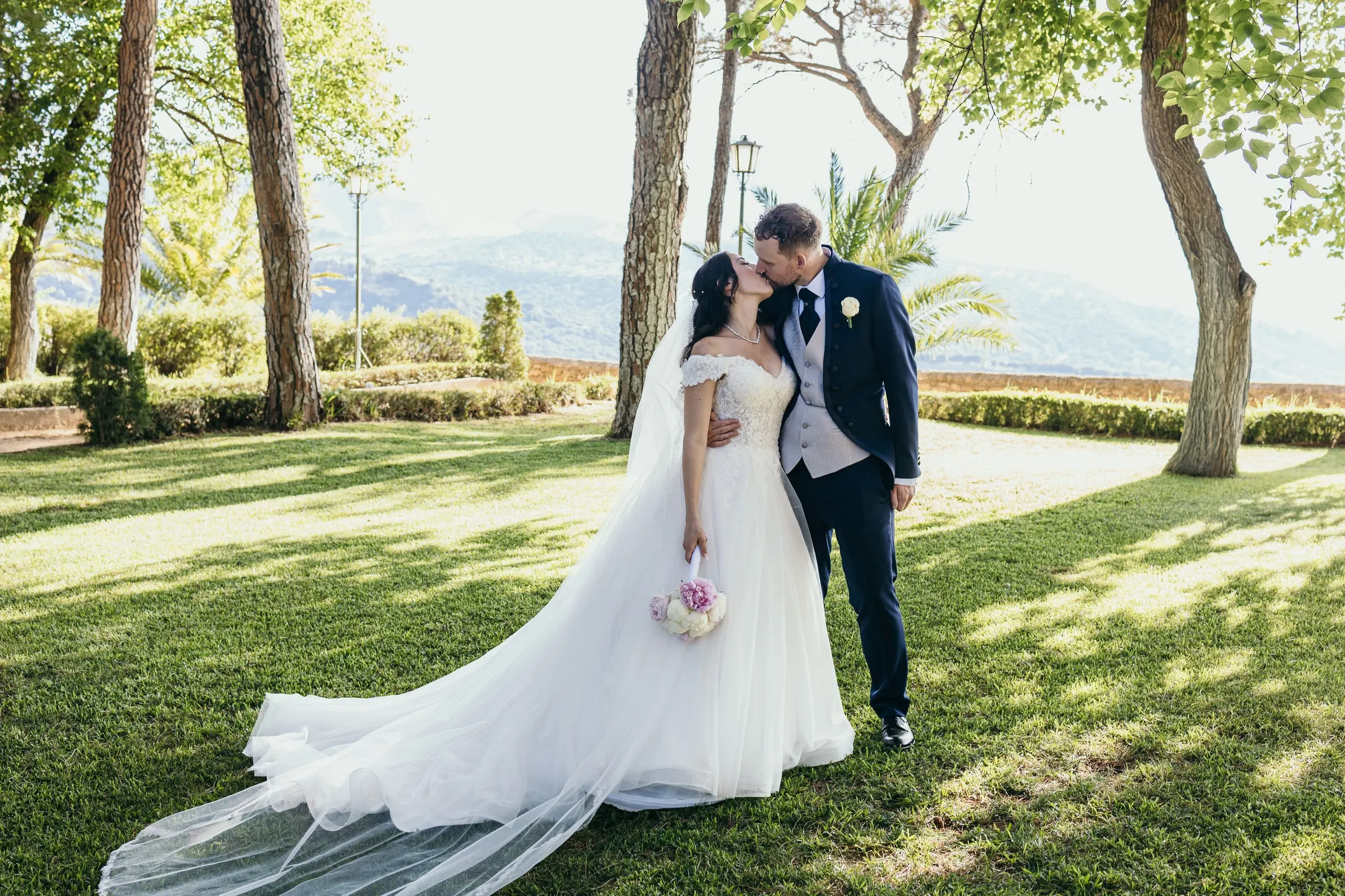Sara and Vincent kiss on a garden path with the Serranía de Ronda behind them