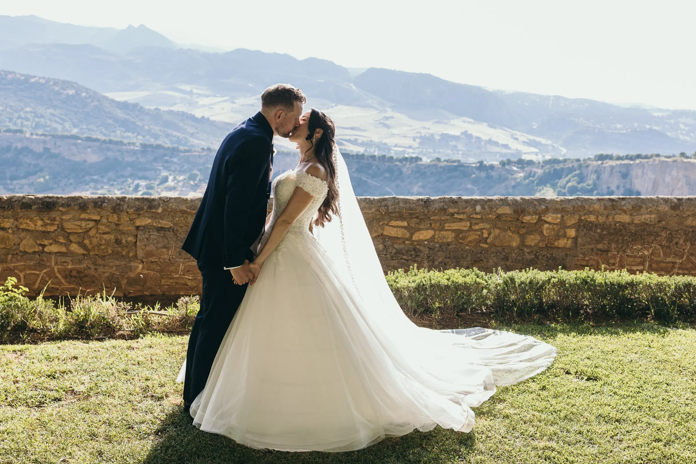 A kiss by the old stone wall with the mountains of the Serranía de Ronda behind