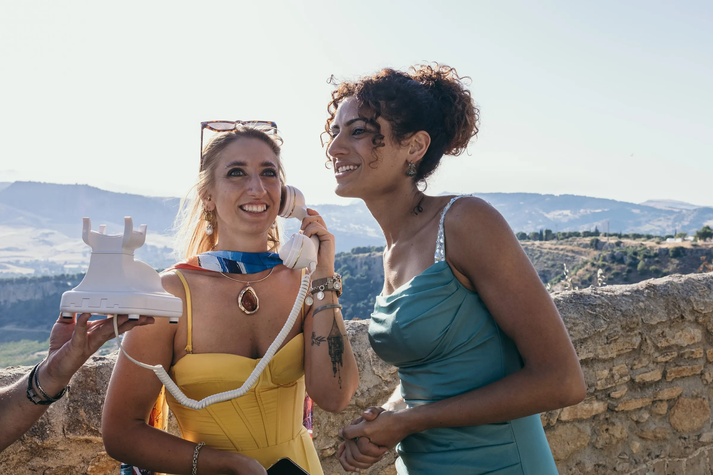 Two guests laugh into the audio guestbook phone at the terrace wall