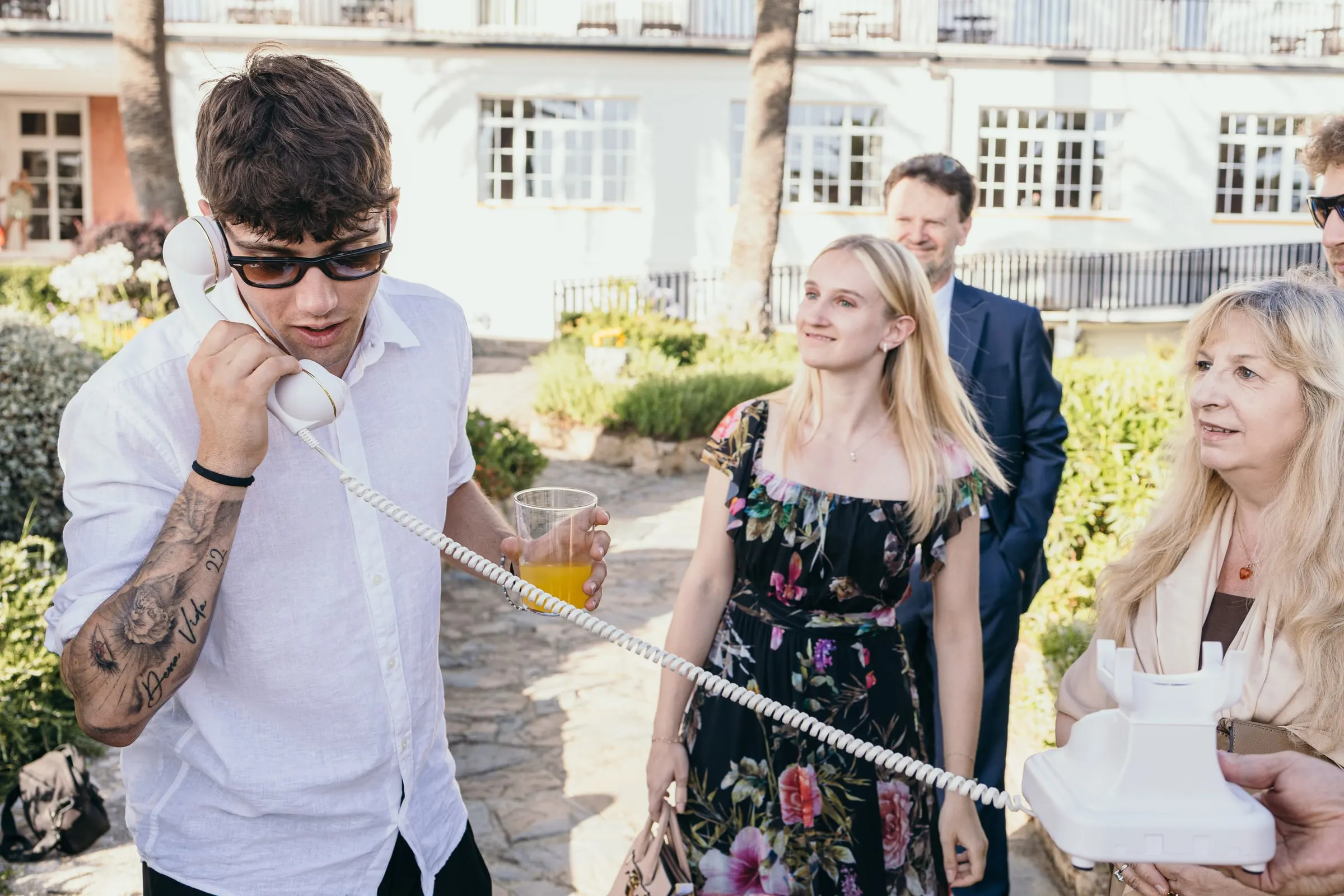 Guests queue for the audio guestbook phone in the garden of the white hotel