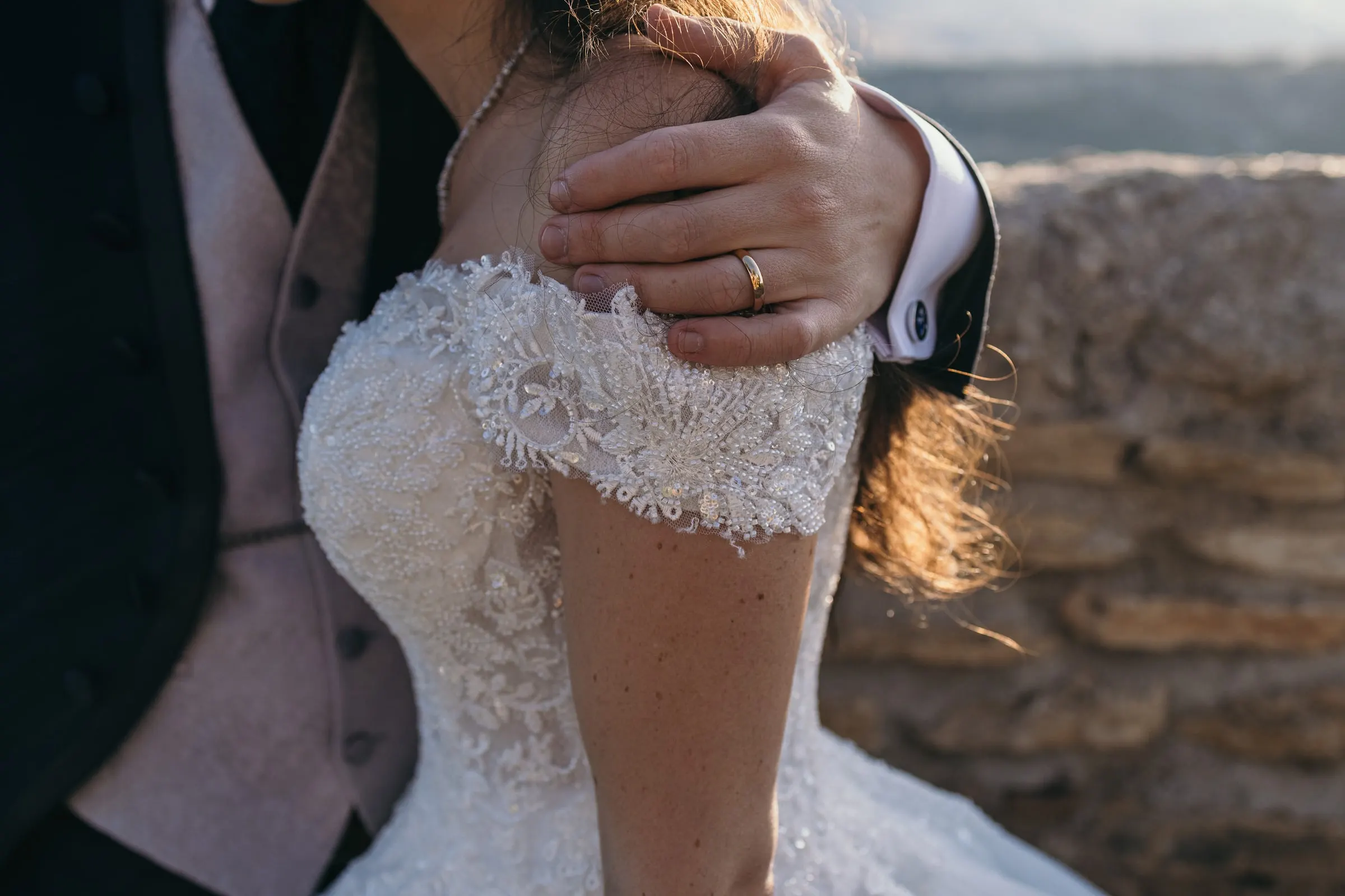Vincent's hand with his wedding ring on Sara's lace shoulder