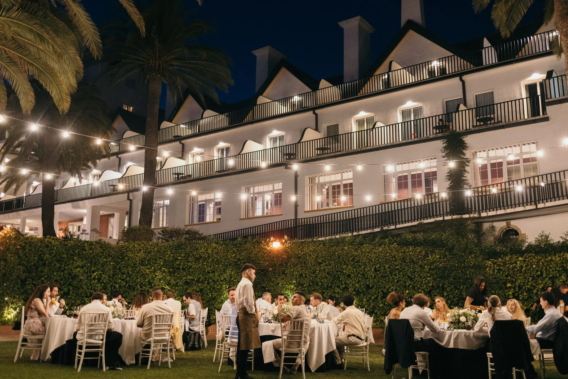 Garden dinner under string lights in front of the white facade of the Hotel Catalonia Reina Victoria, Ronda