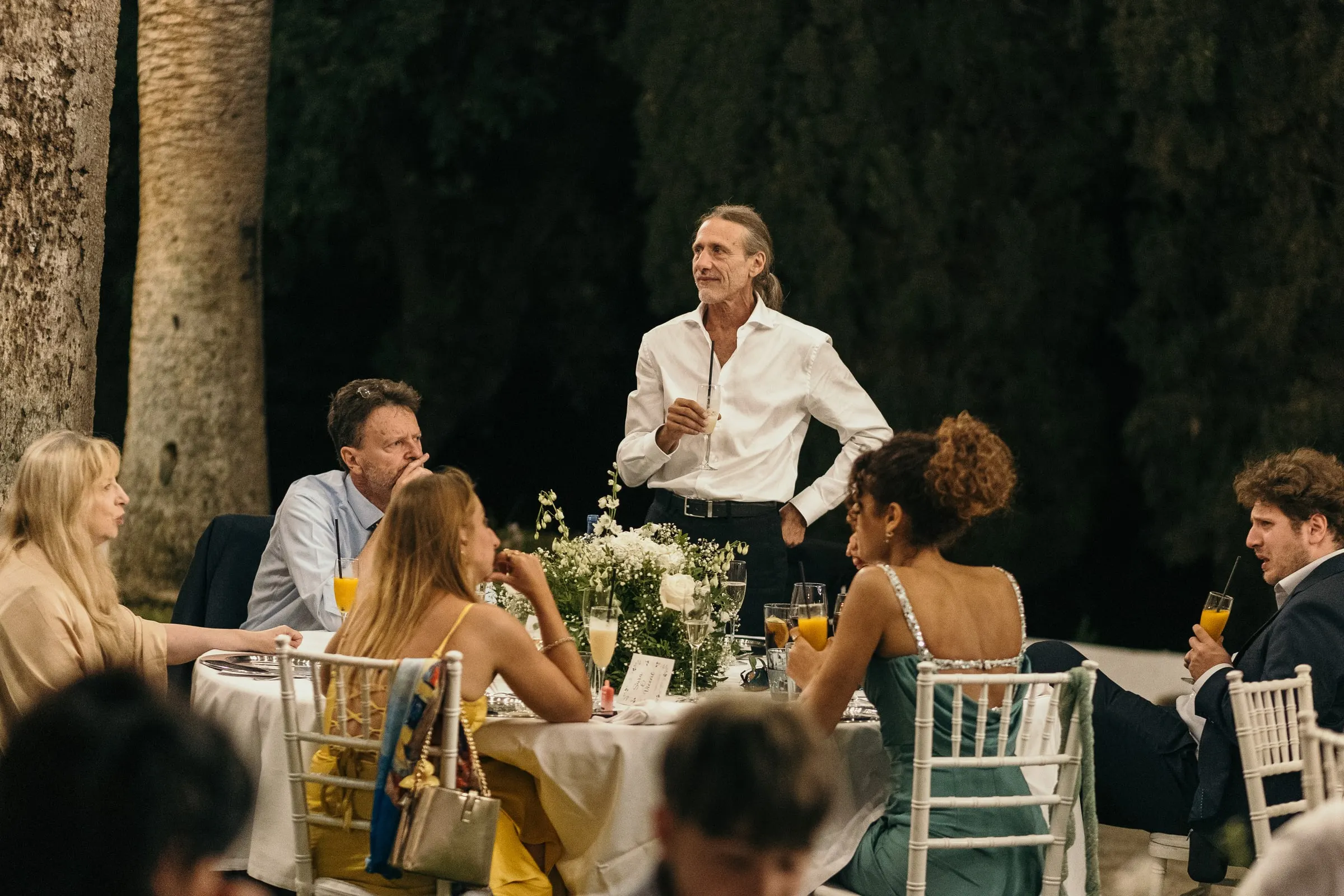 A guest gives a speech at night among the dinner tables