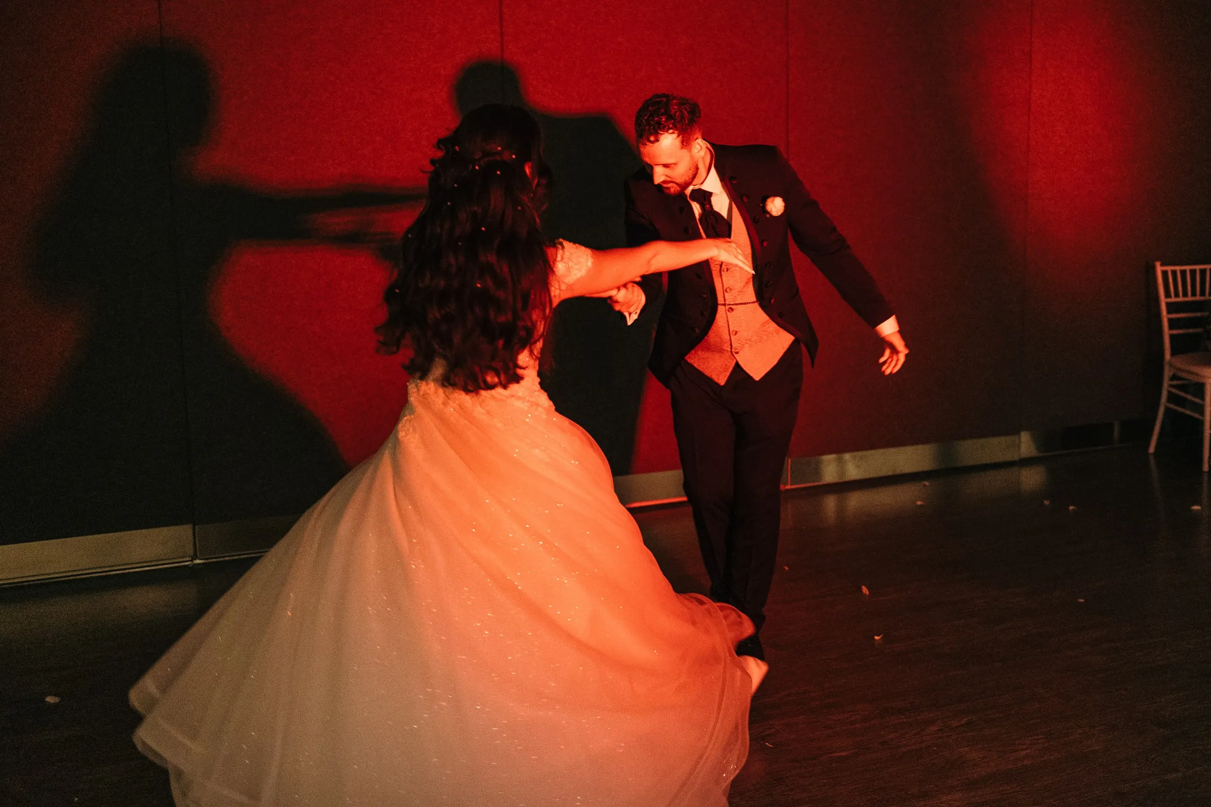 Sara and Vincent dance under red light, their shadows on the wall