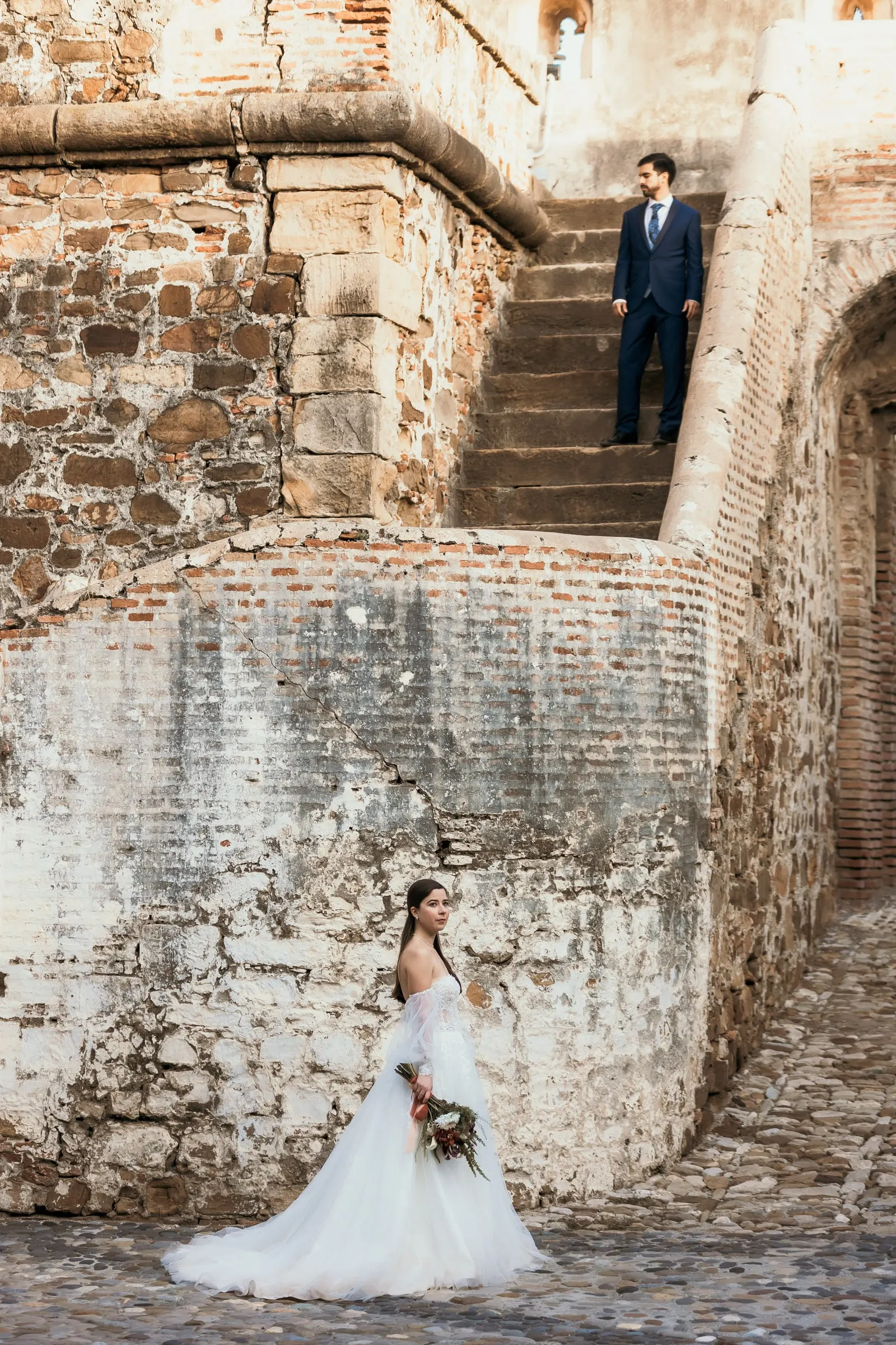 Groom on the stone steps above the bride in the old fortress walls, Cortijo San Francisco, Estepona