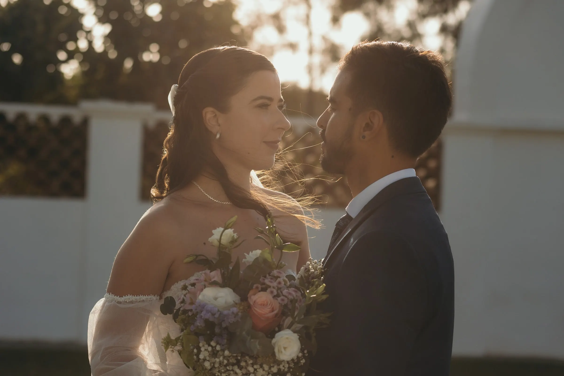 Bride and groom face to face in golden evening light by a white wall, Cortijo San Francisco, Estepona