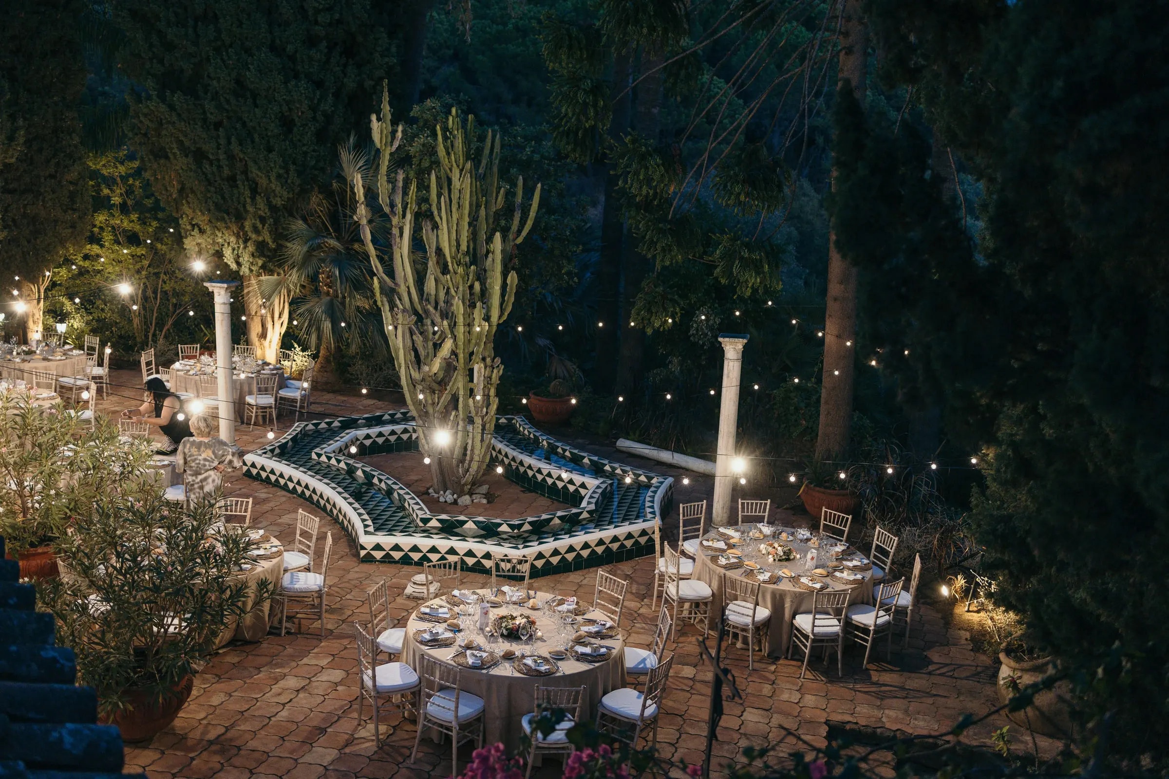 Night view of the tiled courtyard set for dinner, with cacti and lights, Cortijo San Francisco, Estepona