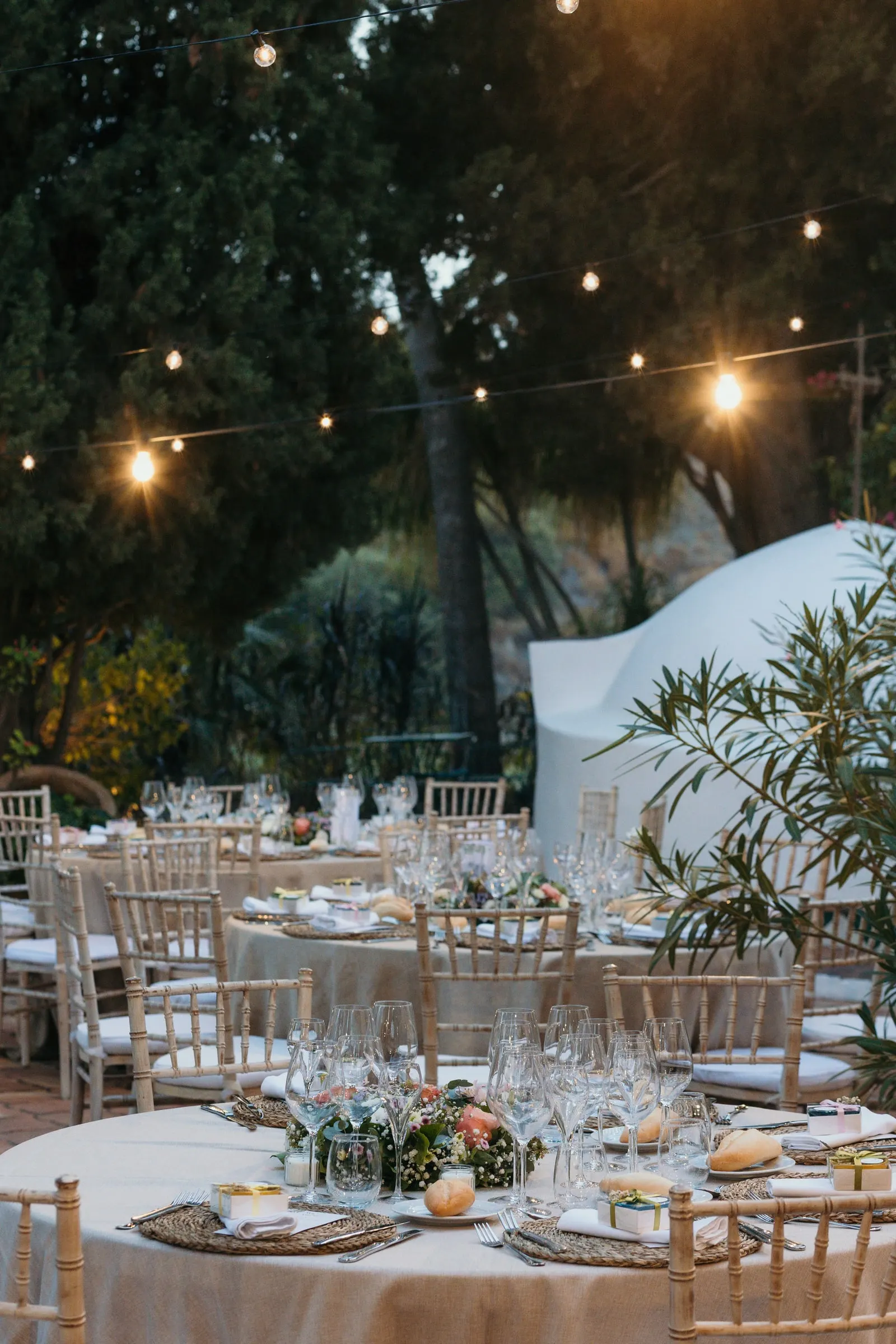 Dinner tables under string lights in the garden at dusk, Cortijo San Francisco, Estepona