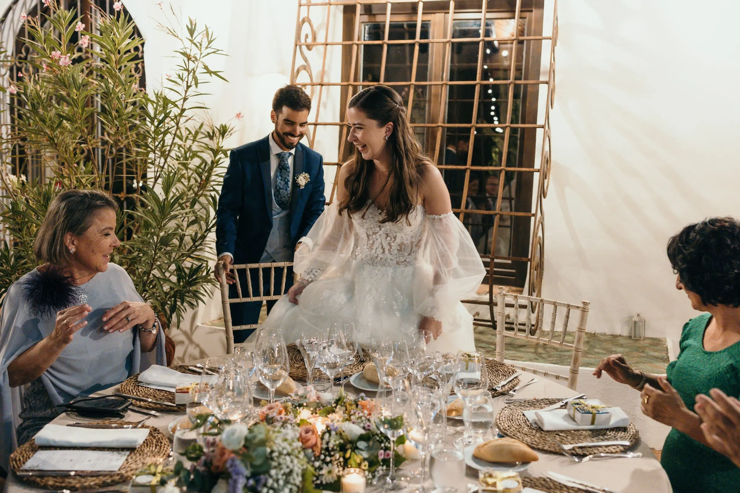 Bride and groom arriving at a guests' table set with flowers, Cortijo San Francisco, Estepona