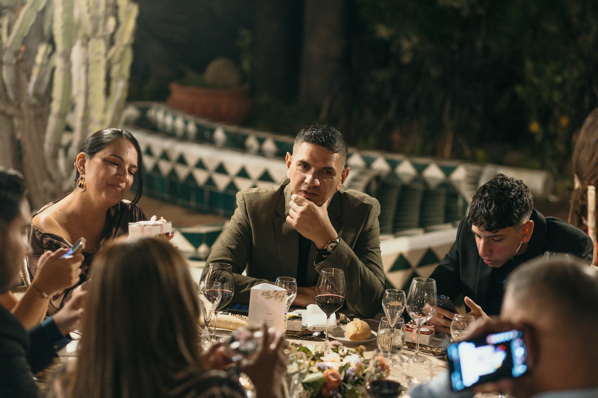 Guests chatting at dinner as one of them films with a phone, Cortijo San Francisco, Estepona