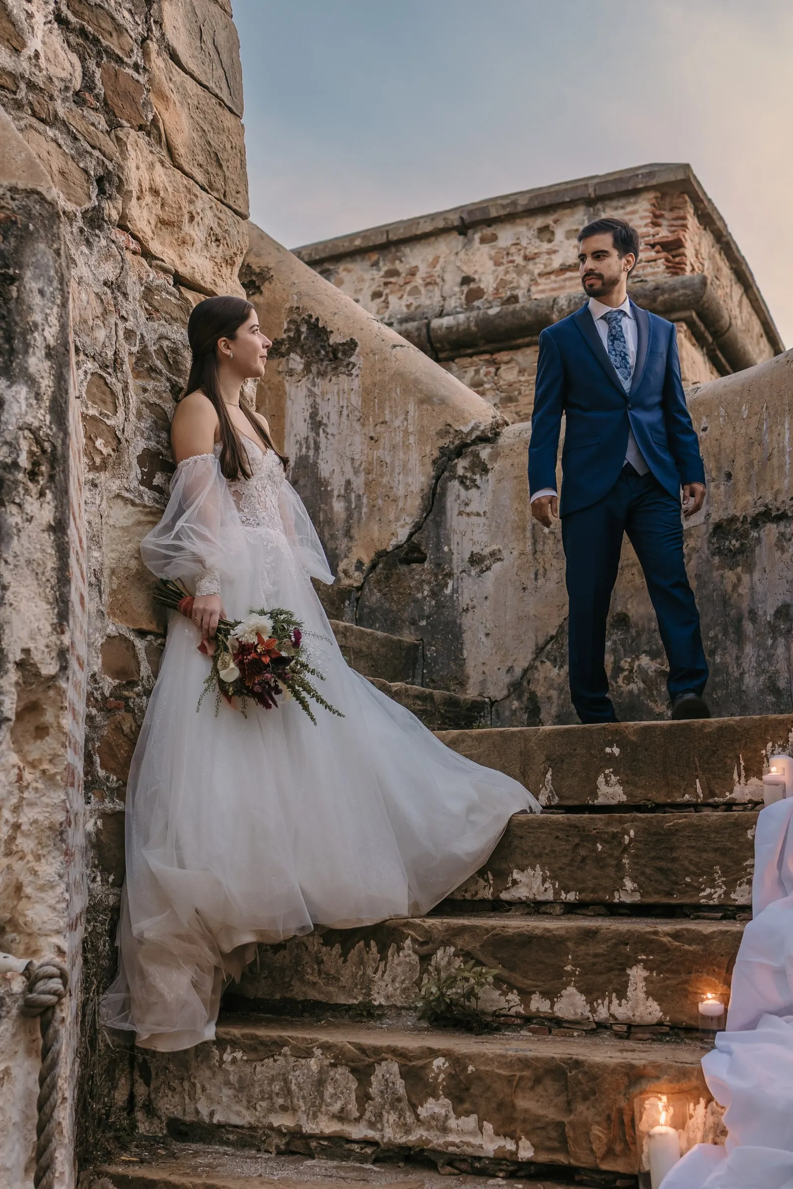 Bride against the old wall and groom on the steps at sunset, Cortijo San Francisco, Estepona