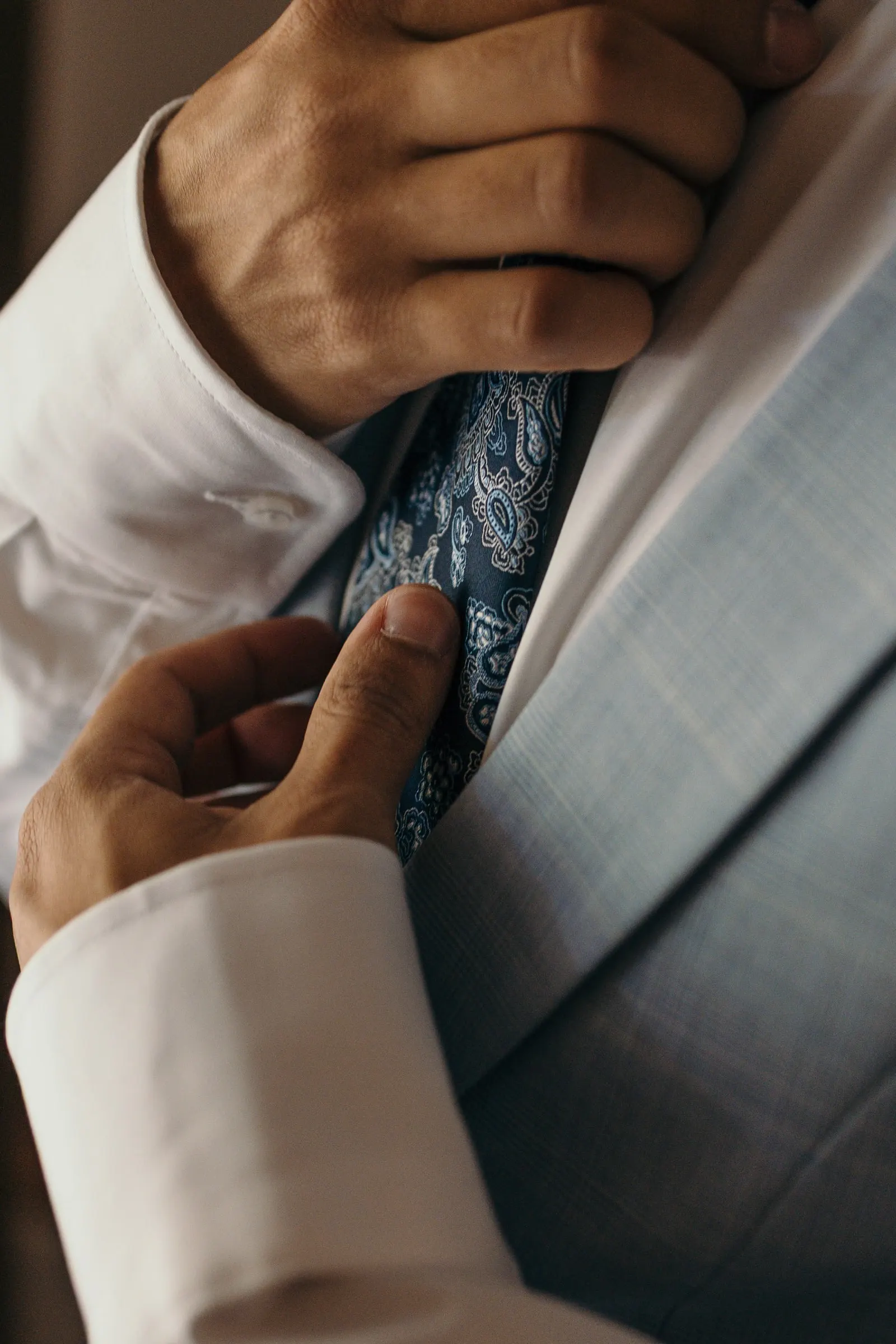 Groom's hands adjusting his paisley tie and grey waistcoat, Cortijo San Francisco, Estepona
