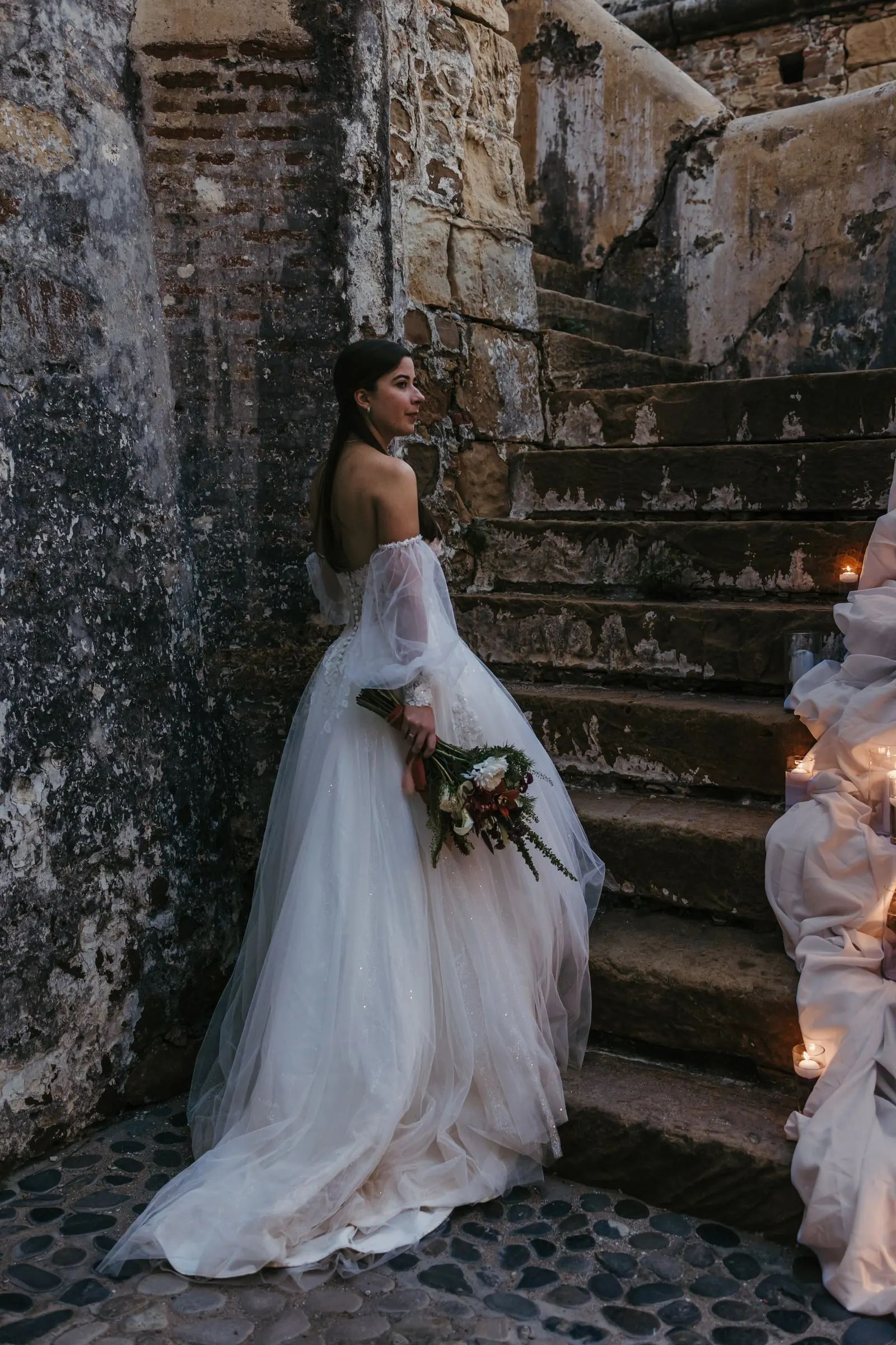 Bride looking over her shoulder at the foot of an old stone staircase, Cortijo San Francisco, Estepona