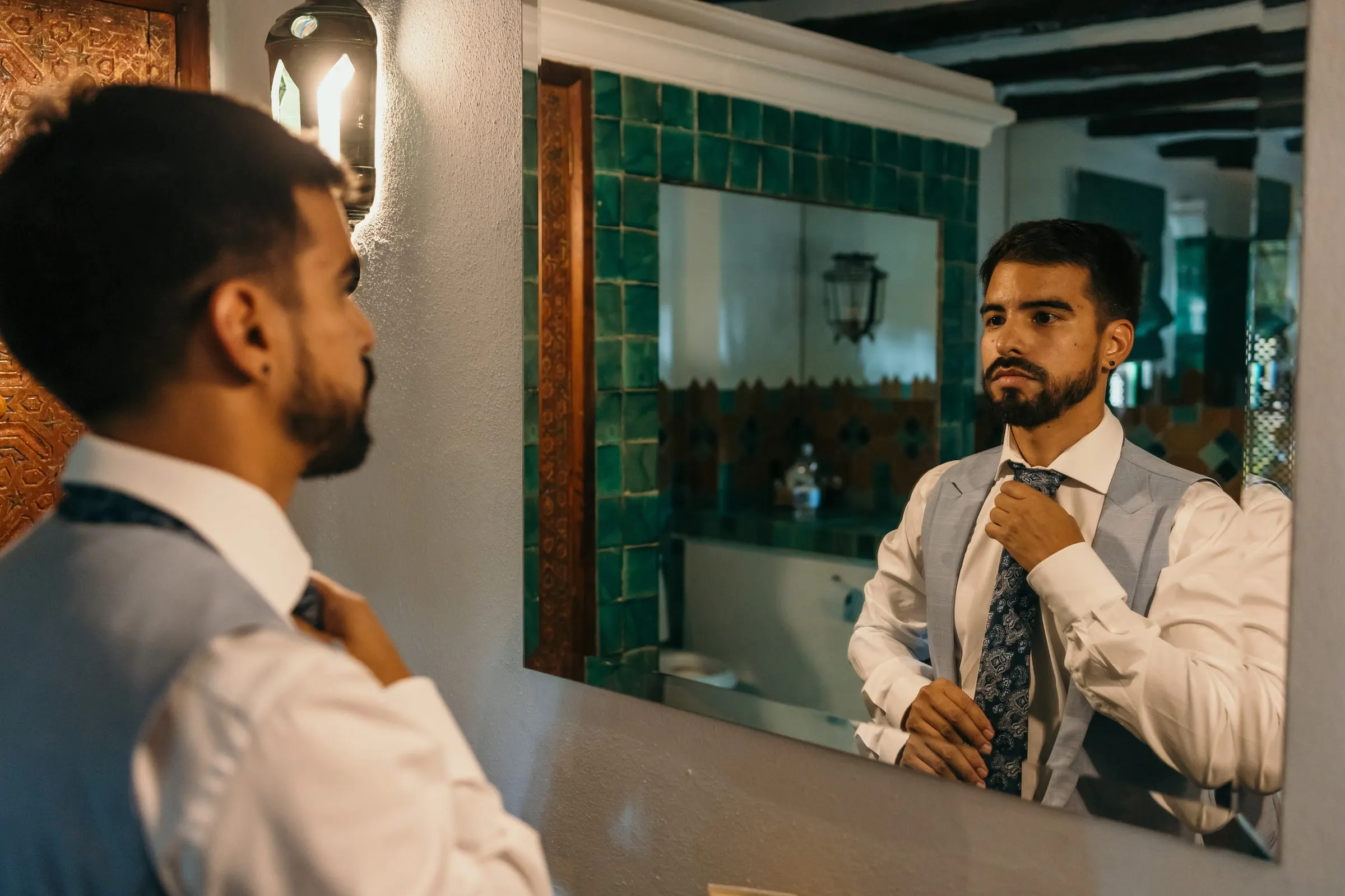 Groom tying his tie in front of the mirror in a tiled bathroom, Cortijo San Francisco, Estepona