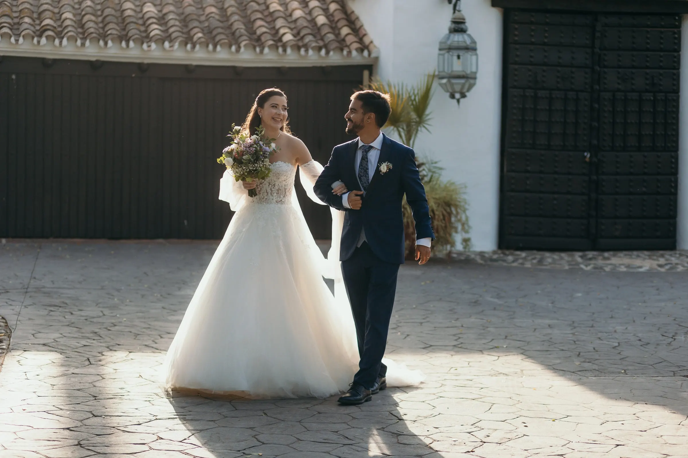 Bride and groom walking out across the sunlit courtyard after the ceremony, Cortijo San Francisco, Estepona