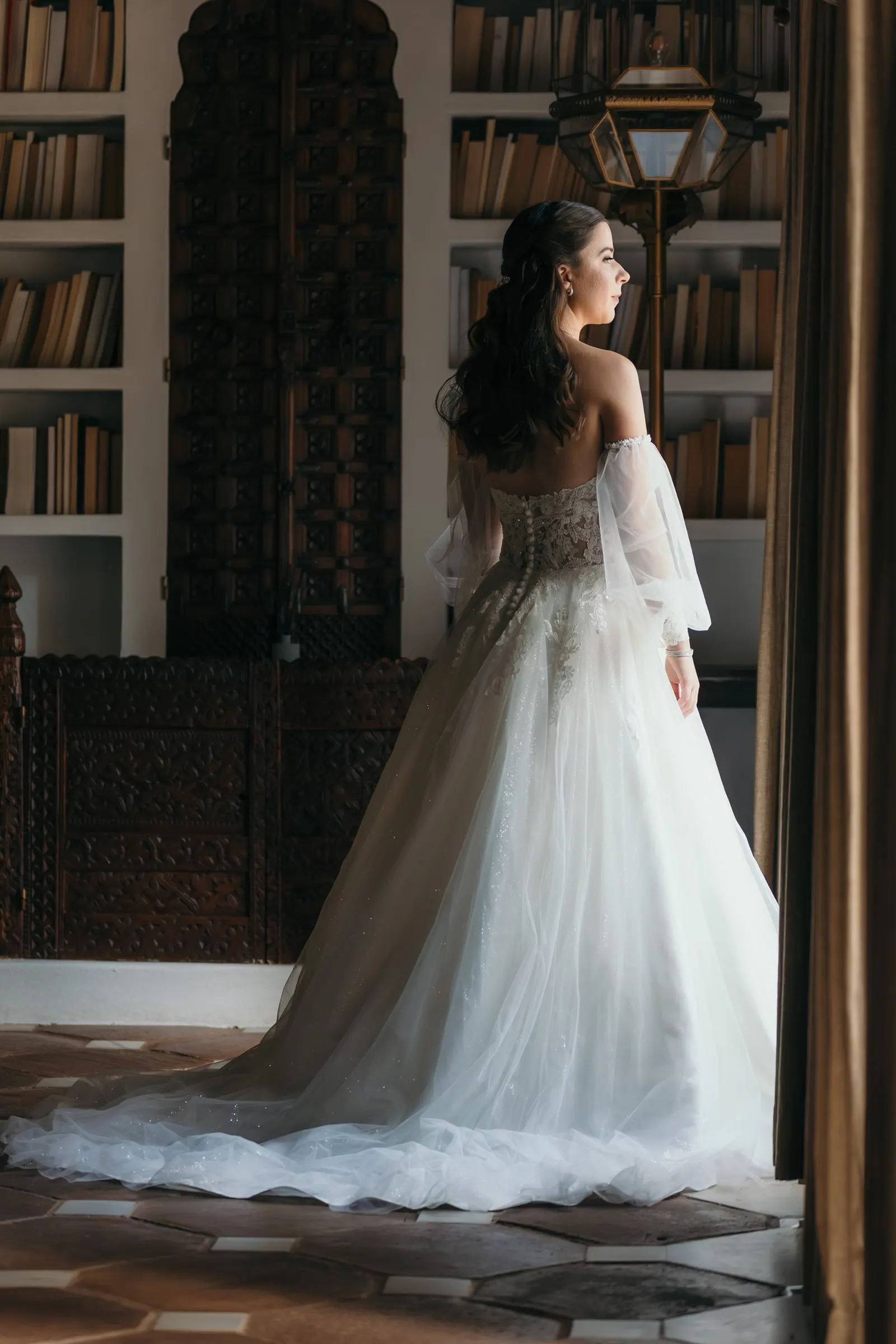 Bride seen from behind in the library, her long train on the tiles, Cortijo San Francisco, Estepona