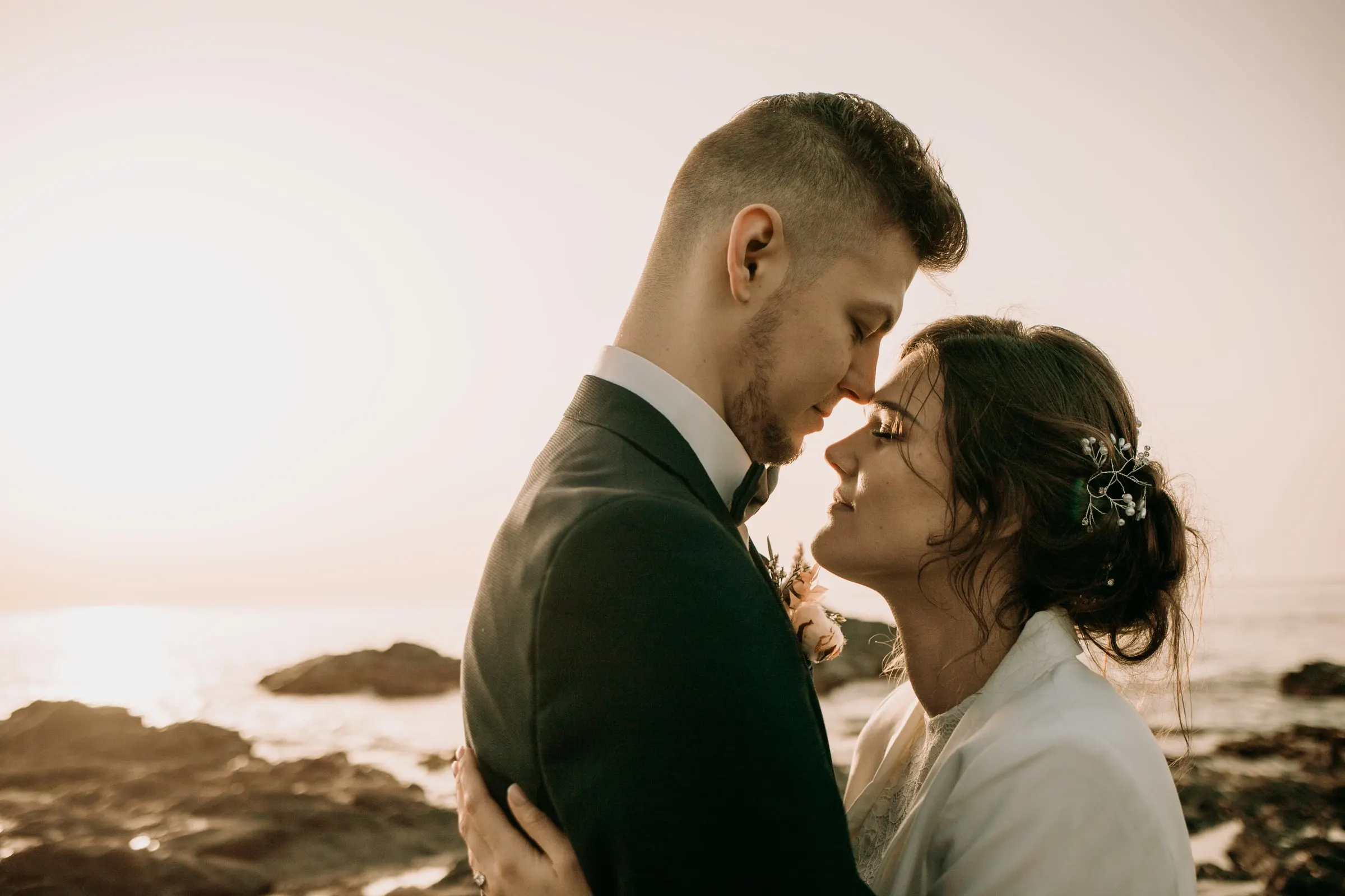 Los novios frente con frente, con el mar brillando detrás