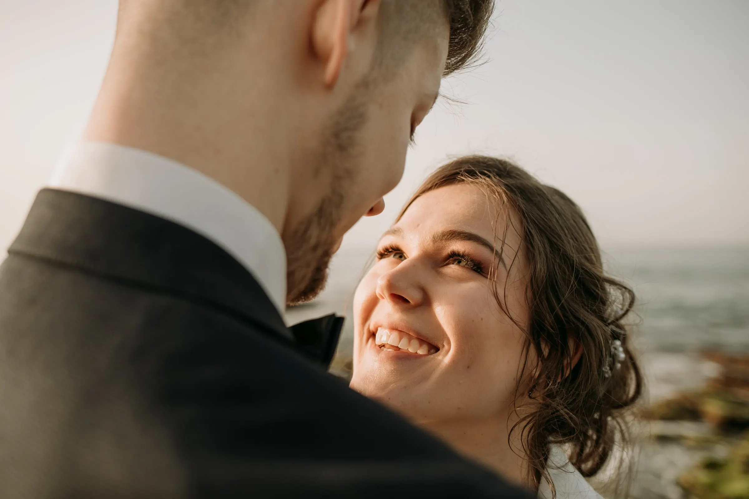 La novia sonríe con los ojos cerrados, mejilla con mejilla con el novio