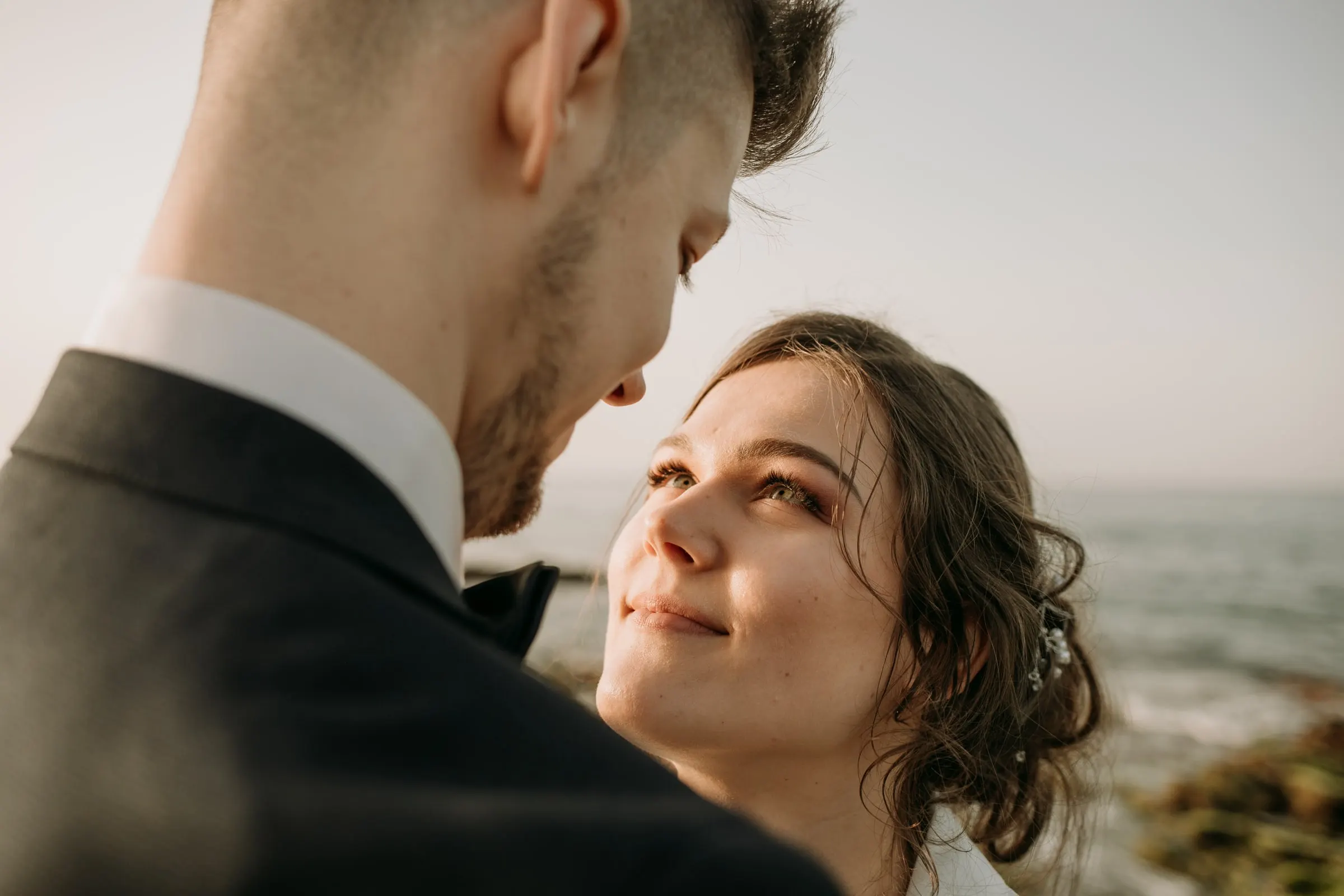 Retrato cercano de la novia mirando al novio junto al mar