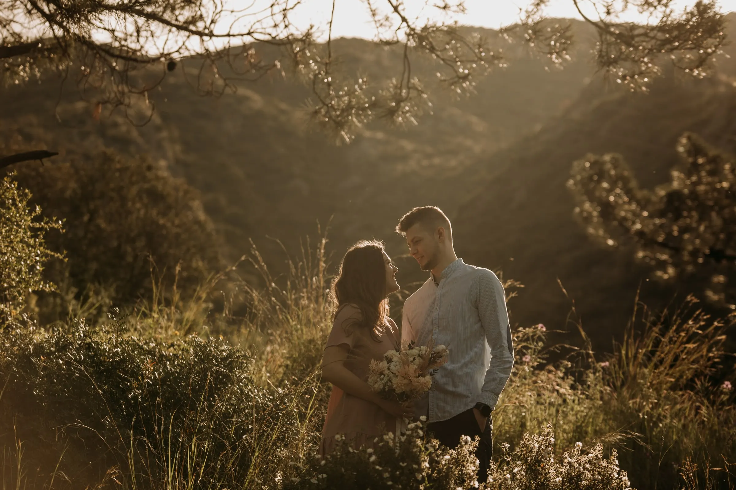 La pareja entre la hierba alta de una ladera con la sierra detrás, preboda en la Costa del Sol
