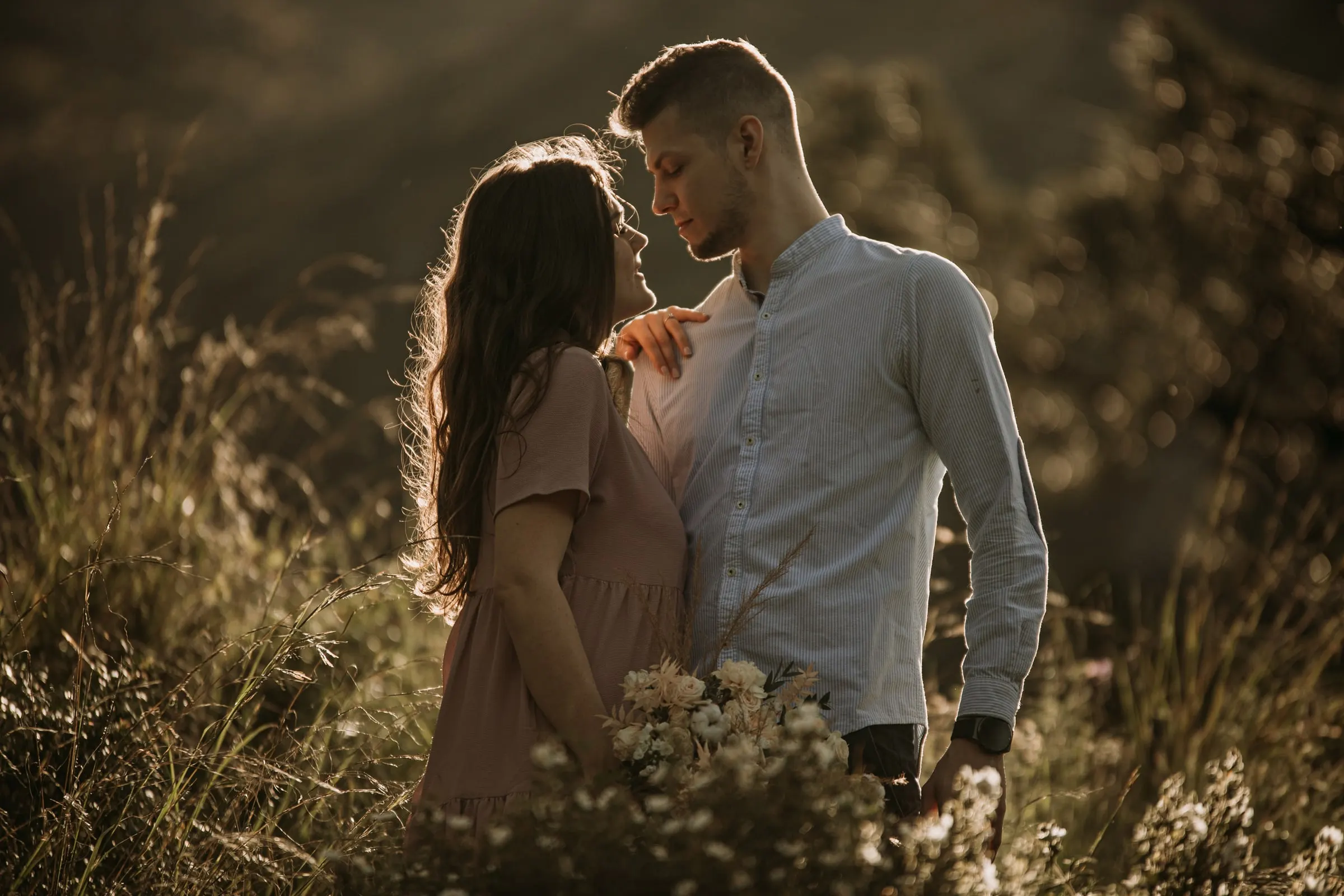 La futura novia mira a su prometido con la mano en su hombro, con la luz de la tarde