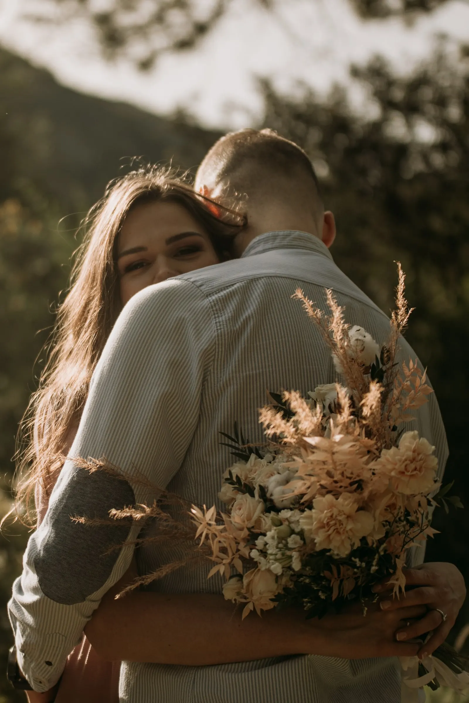 La futura novia abraza a su prometido y sonríe por encima de su hombro