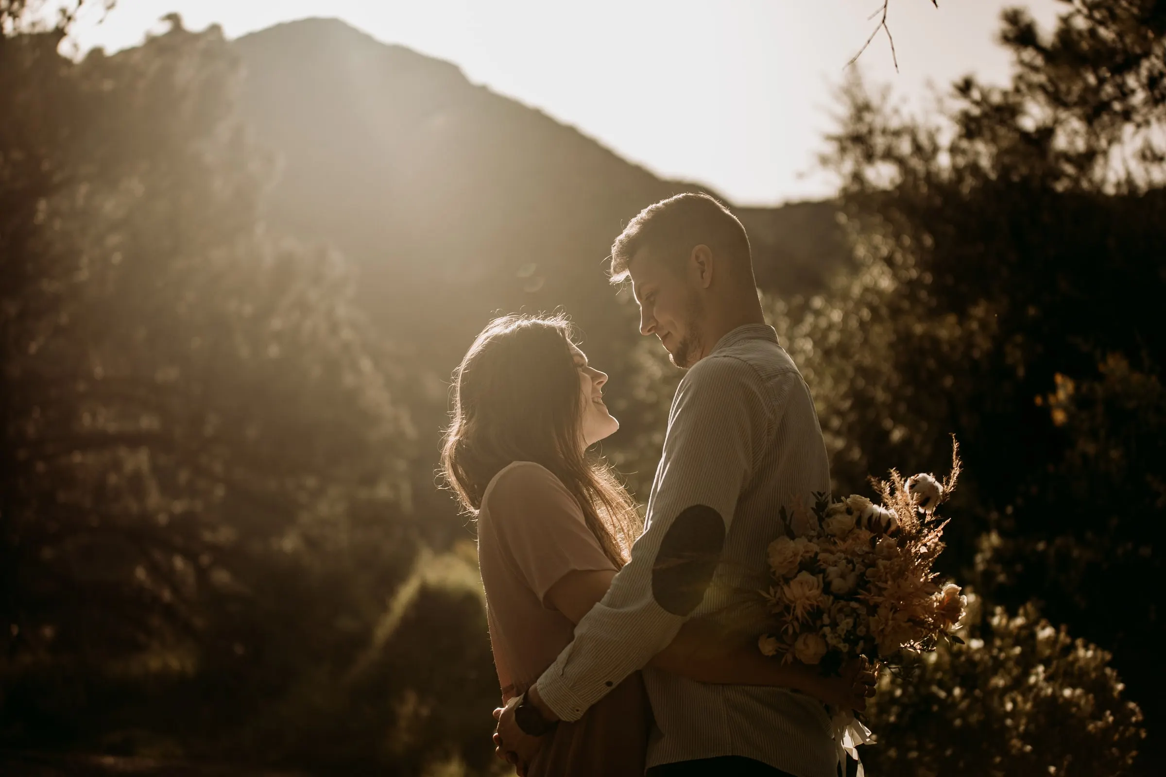 La pareja se mira, con el sol sobre la cresta de la sierra detrás