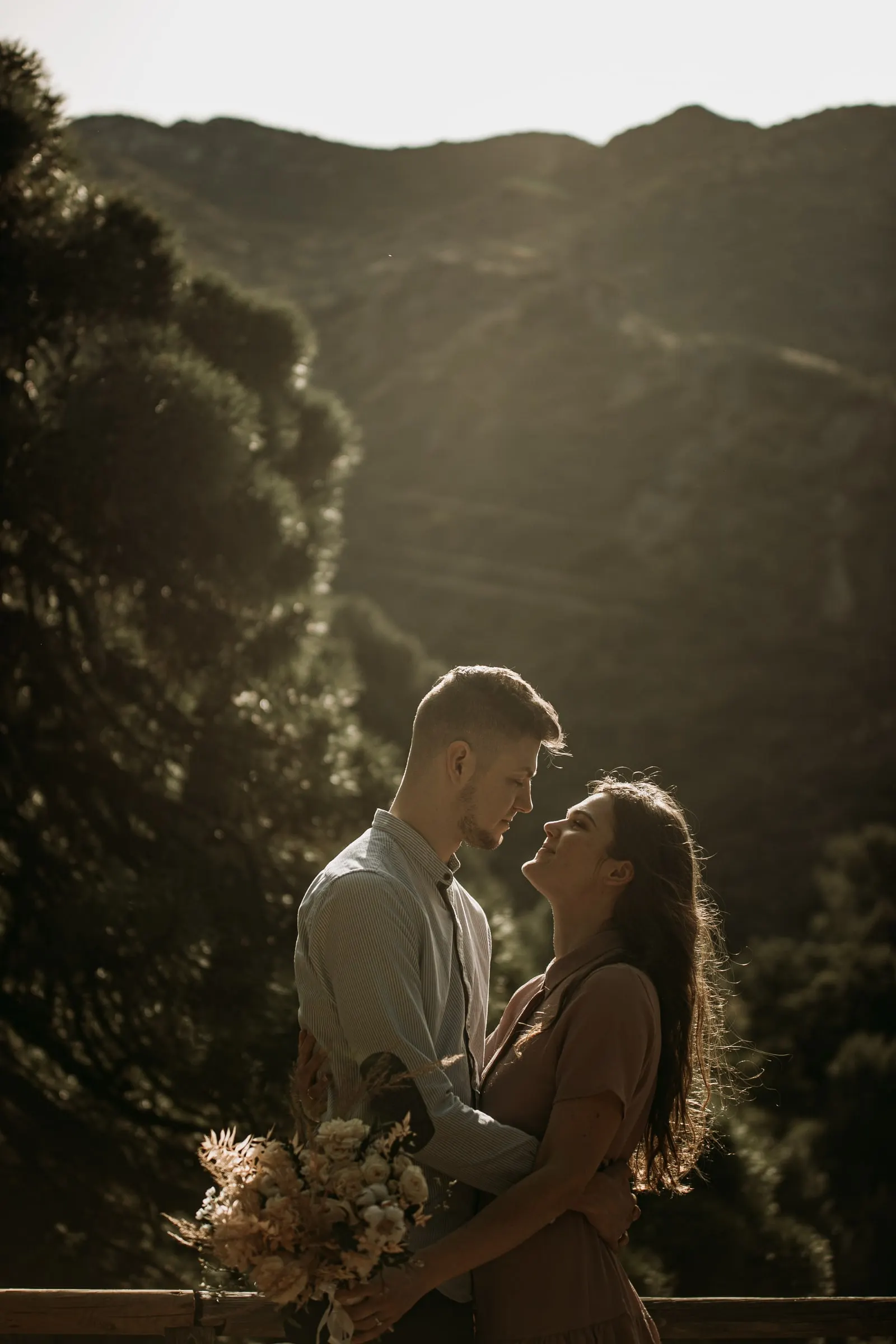 La pareja frente a frente con su ramo, con la ladera del monte detrás